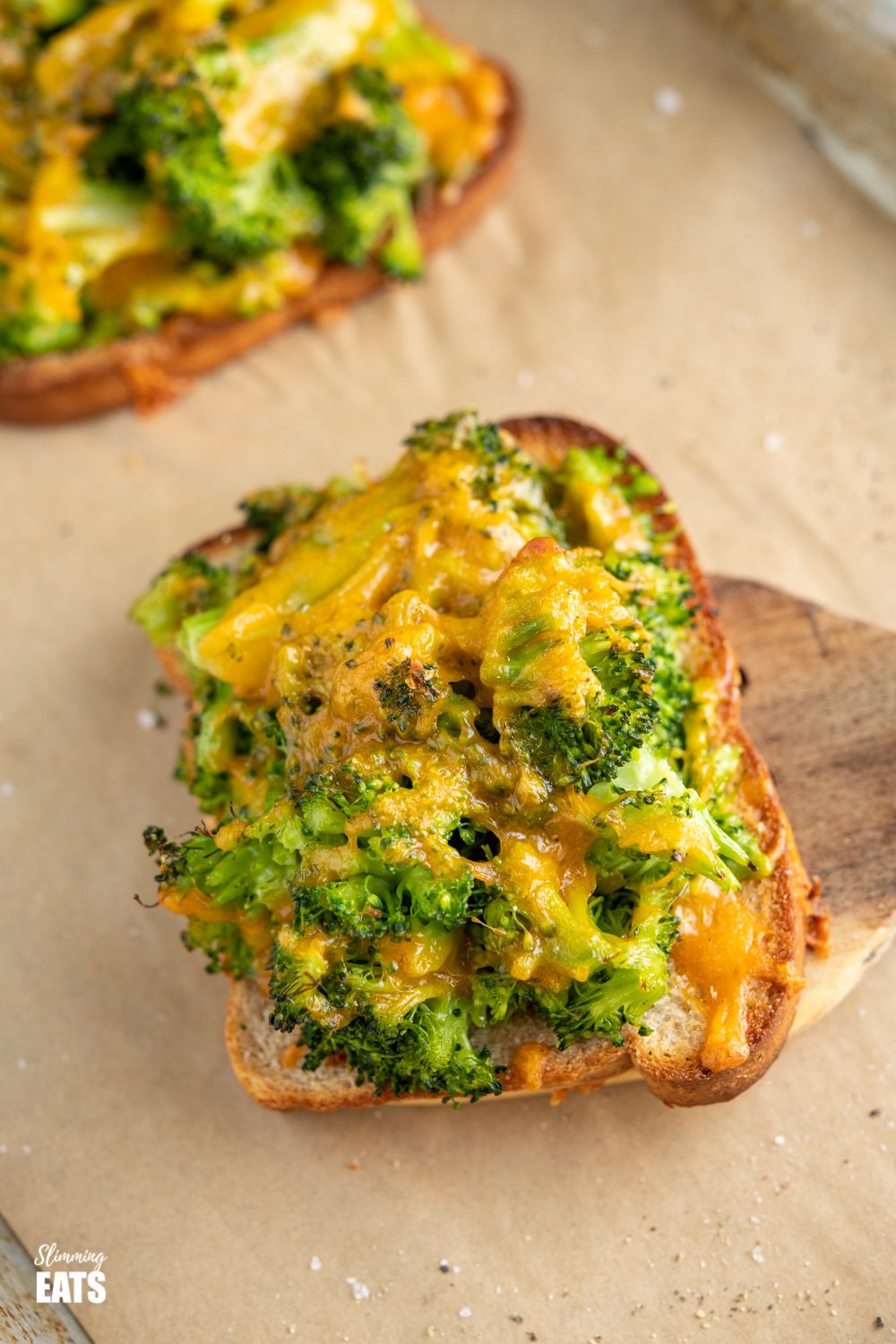 Cheesy Broccoli Avocado Toasts - crispy oven baked toast, topped with cheesy broccoli goodness for a perfect any time of day combo. #broccoli #avocado #slimmingeats #weightwatchers #cheddar close up of cheesy broccoli avocado toasts on baking tray