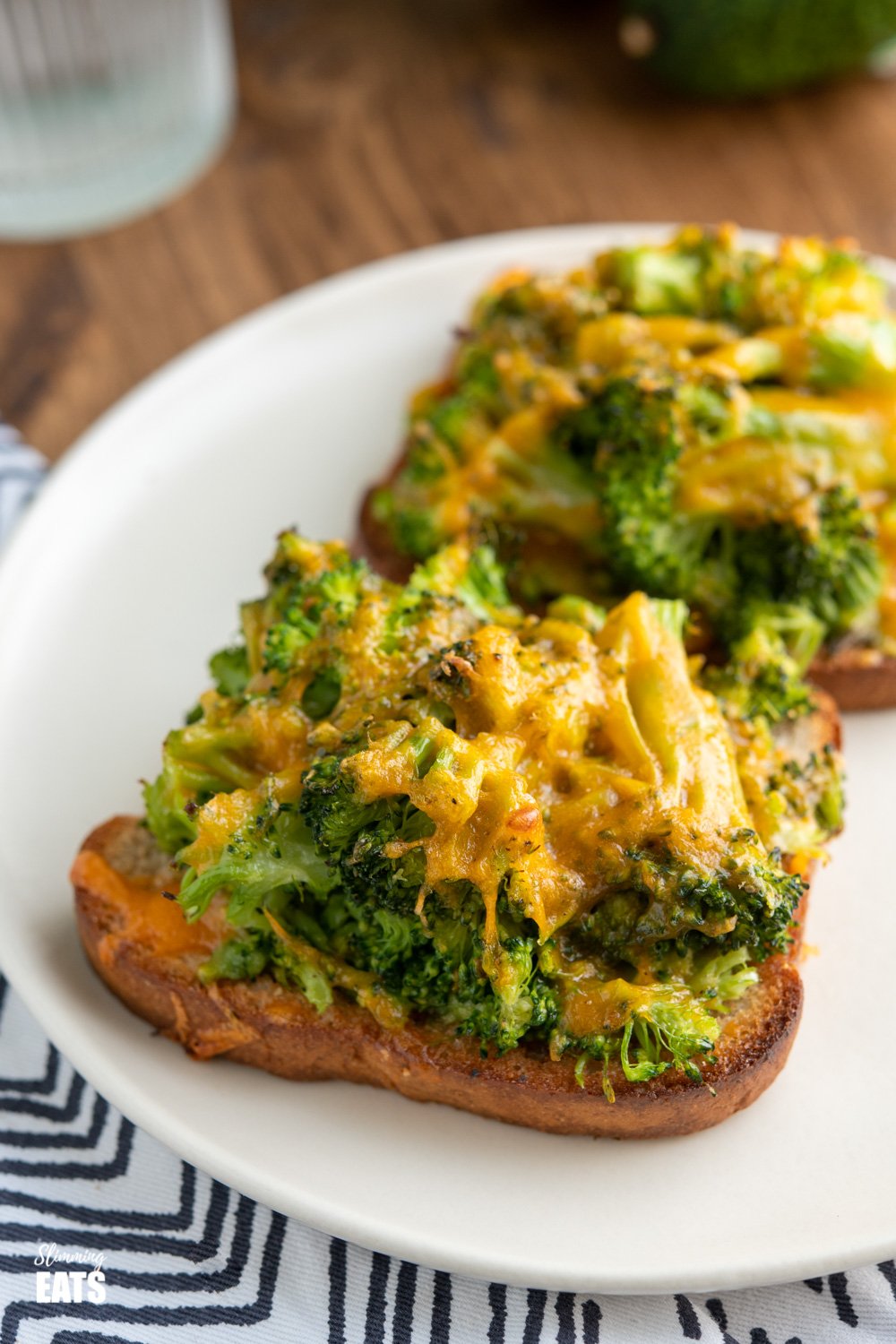 Cheesy Broccoli Avocado Toasts - crispy oven baked toast, topped with cheesy broccoli goodness for a perfect any time of day combo. #broccoli #avocado #slimmingeats #weightwatchers #cheddar cheese broccoli avocado toasts on a white plate