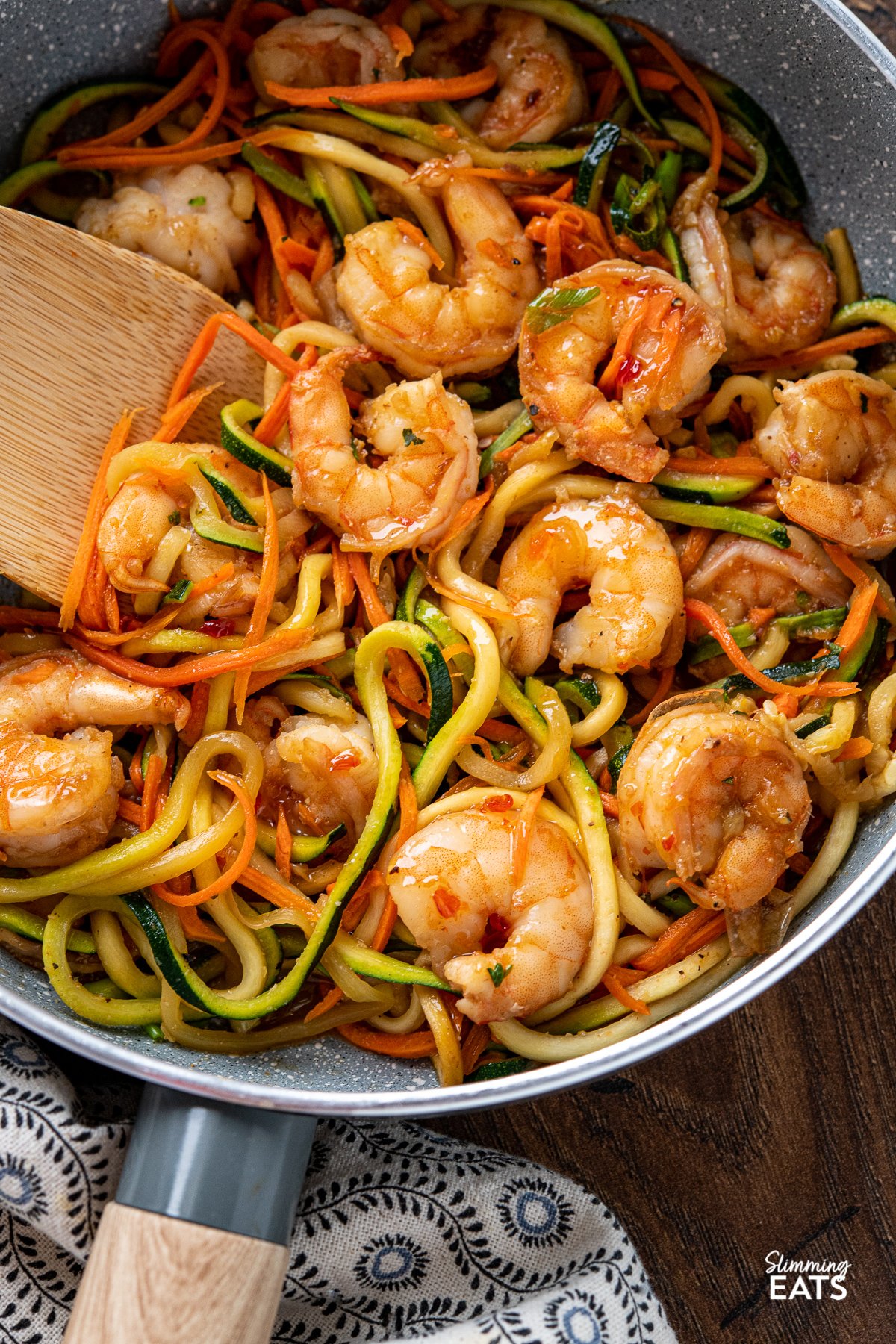 Quick Sweet Chilli Prawns with Vegetable Noodles - a quick and easy stir fry recipe that is lighter on the carbs with some healthy spiralized vegetable noodles. Slimming World and Weight Watchers friendly close up of Quick Sweet Chilli Prawns with Vegetable Noodles in a grey non stick frying pan