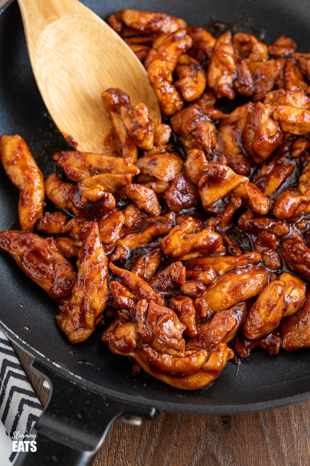 close up of sweet and sticky chicken in black frying pan