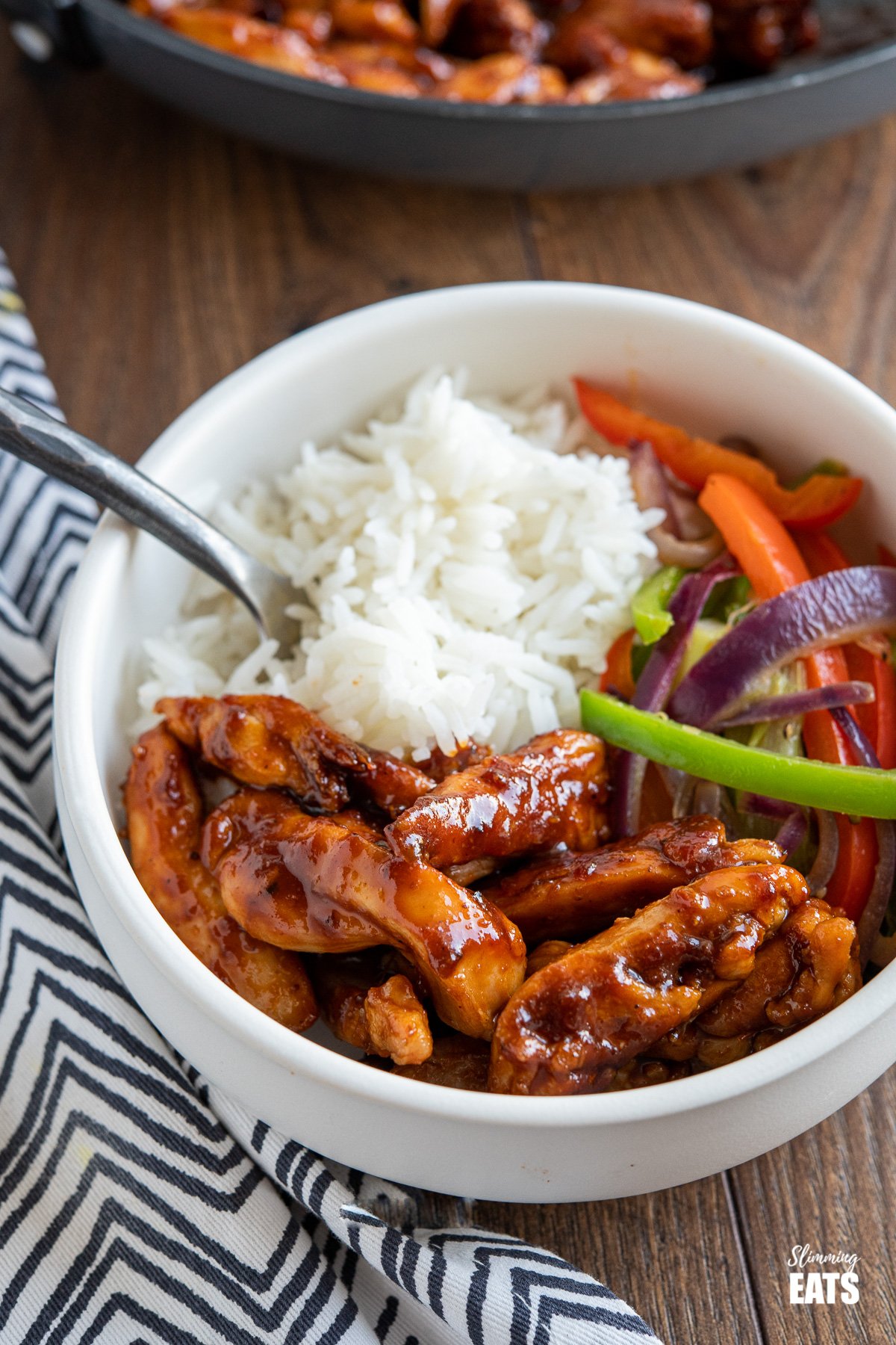 Sweet and Sticky Chicken - tender strips of seasoned chicken thigh in a lick the spoon sweet and sticky sauce. #SLIMMINGWORLD #WEIGHTWATCHERS #CHICKEN #SWEET #STICKY #GLUTENFREE #DAIRYFREE sweet and sticky chicken in white bowl with rice and vegetables