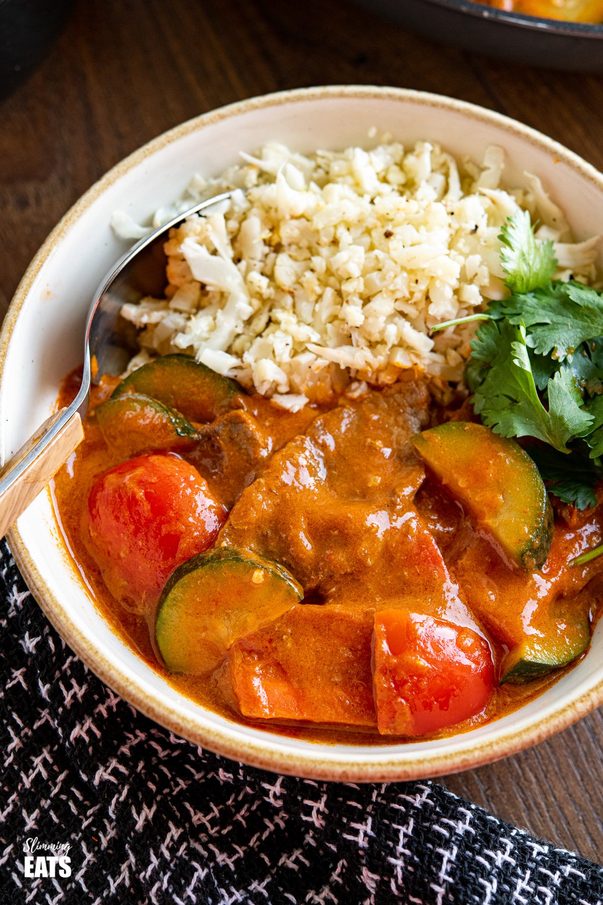 Thai Red Beef Curry in a cream bowl with cauliflower rice and cilantro