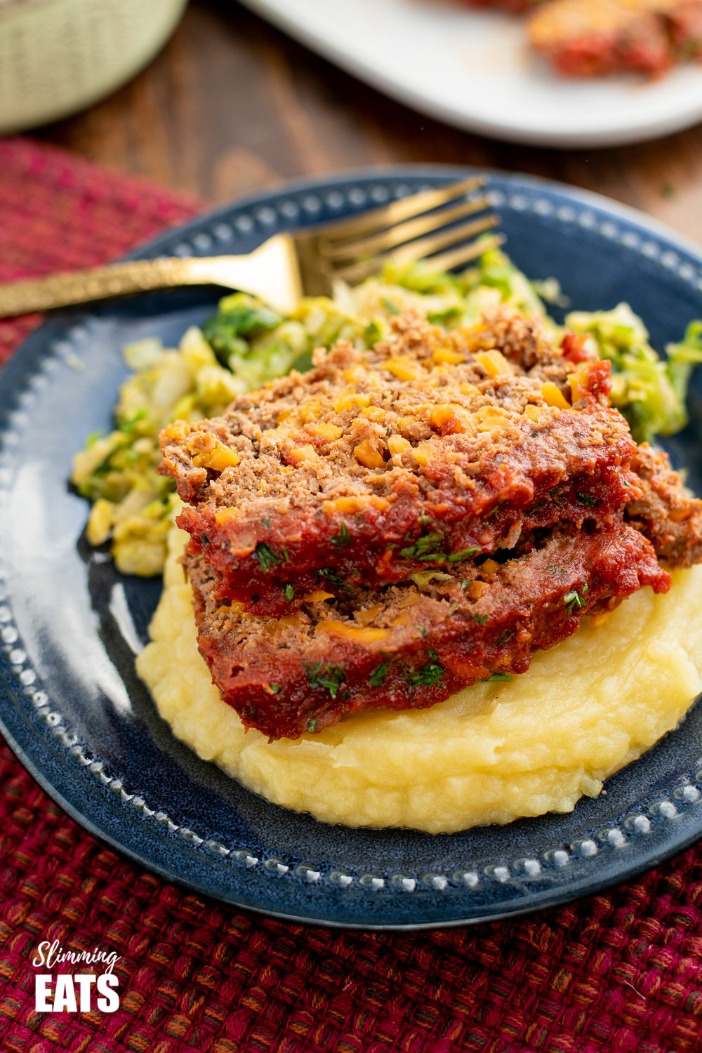 beef and sweet potato meatloaf over mashed potatoes on a navy blue plate. 