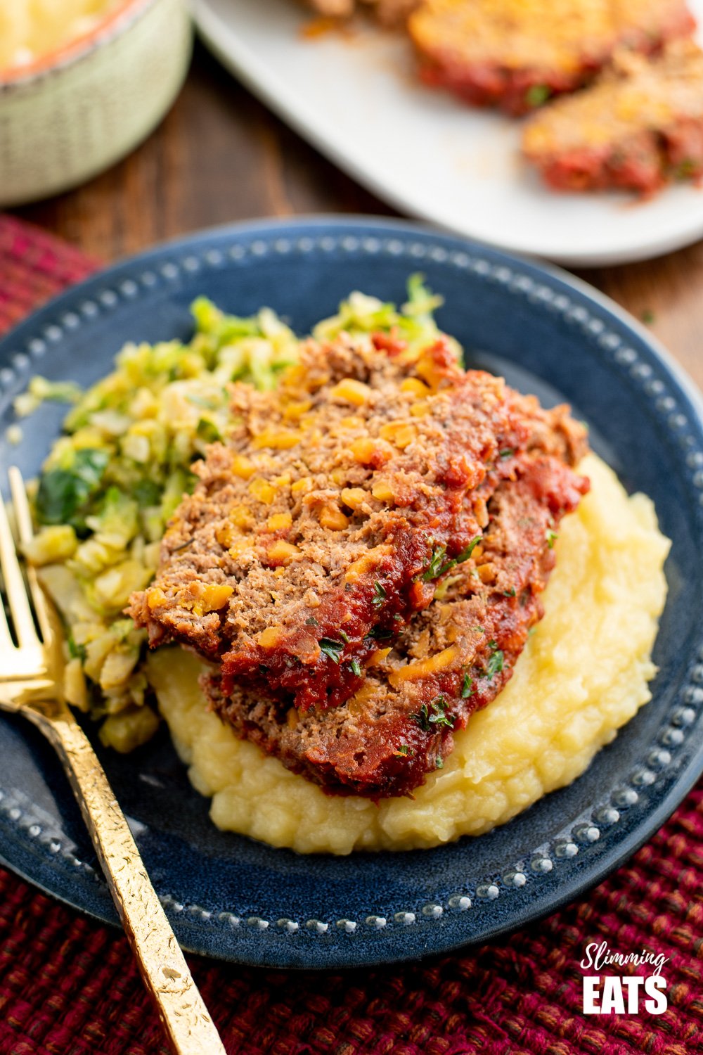 2 slices of beef and sweet potato meatloaf over mashed potato on a navy blue plate.