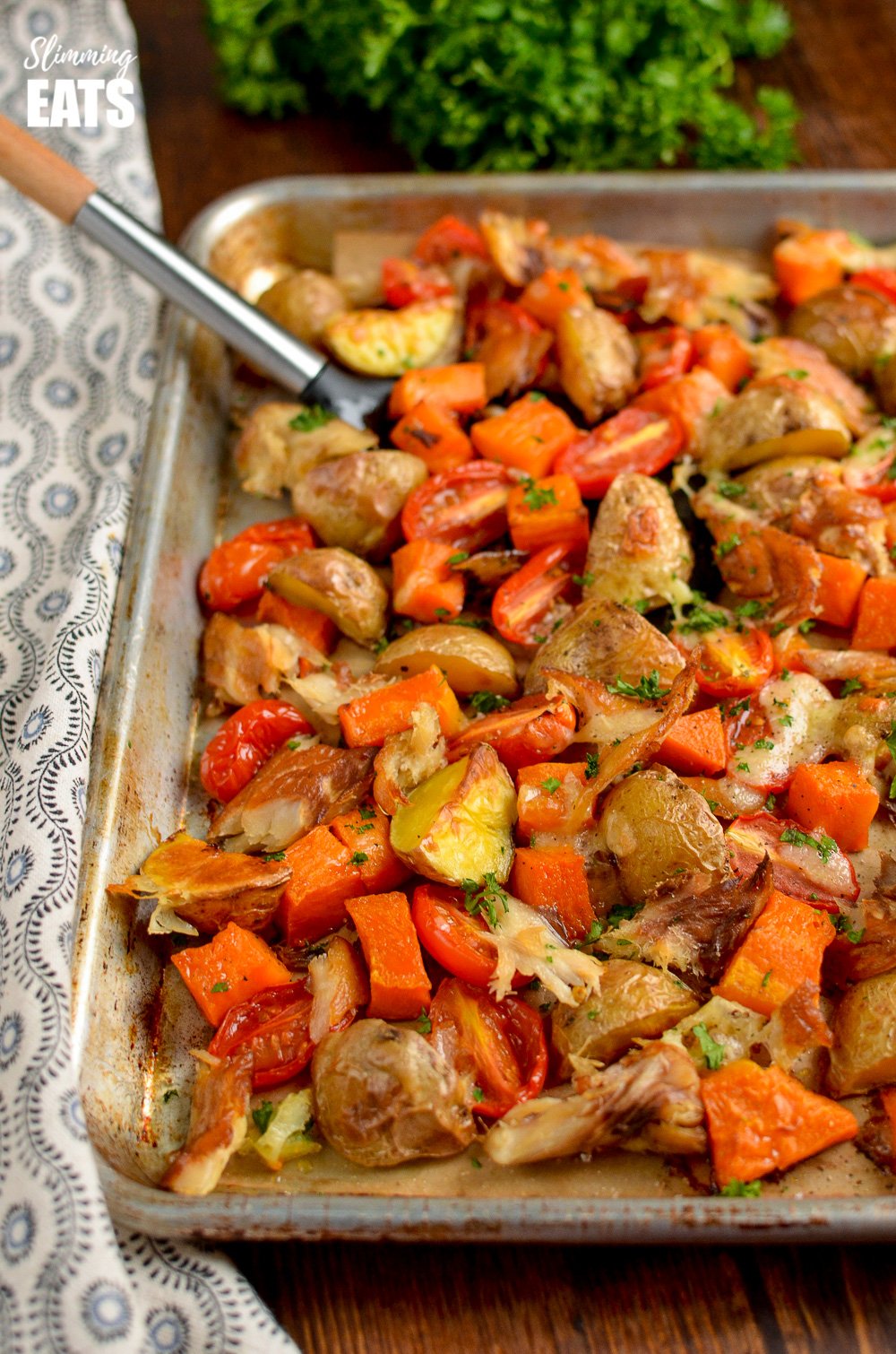 Smoked Mackerel Bake - delicious smoky fish with golden roast potatoes, juicy tomatoes and sweet butternut squash finished off with a cheesy topping. Gluten free, dairy free, paleo, Whole30, Slimming Eats and Weight Watchers friendly smoked mackerel bake on a baking tray with spatula