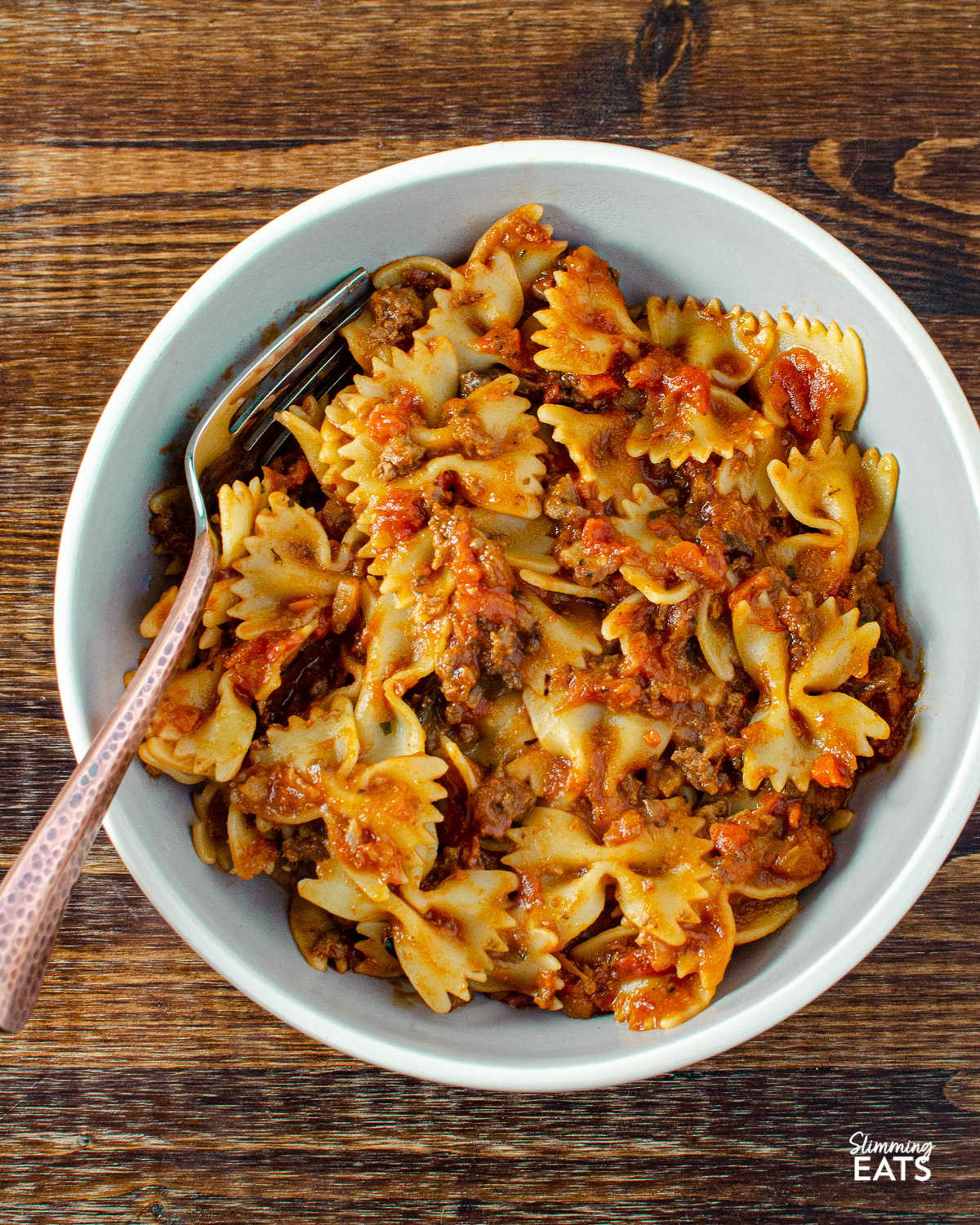 meat pasta bowls in grey bowl without salad silver and gold fork to side