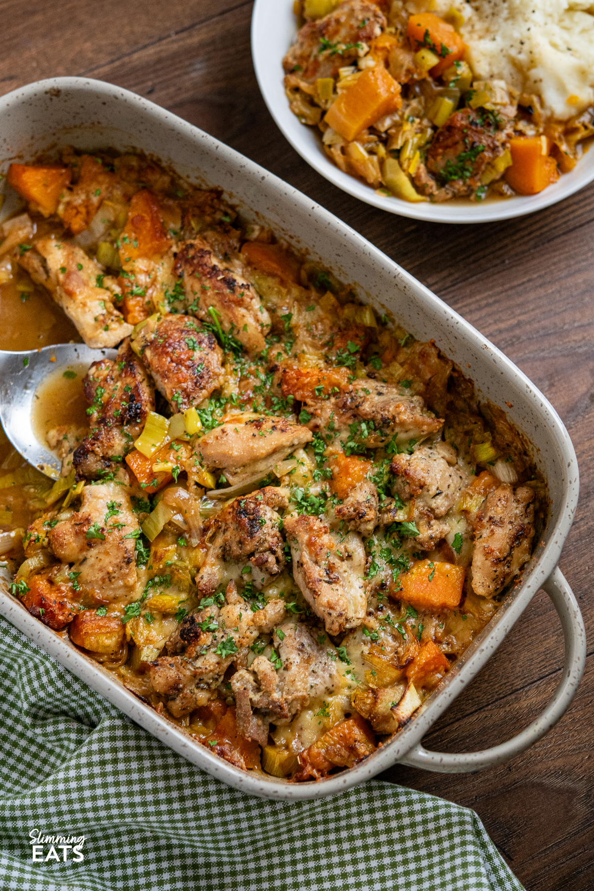 Chicken, Leek and Butternut Squash Bake double handled grey oven proof dish with serving in a bowl with mashed potatoes