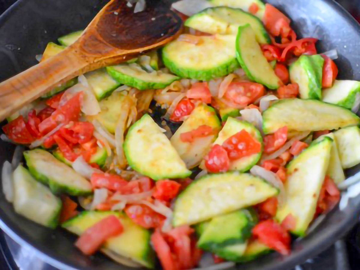 Mayan Heirloom Squash with Tomatoes and Basil being sauteed in a pan