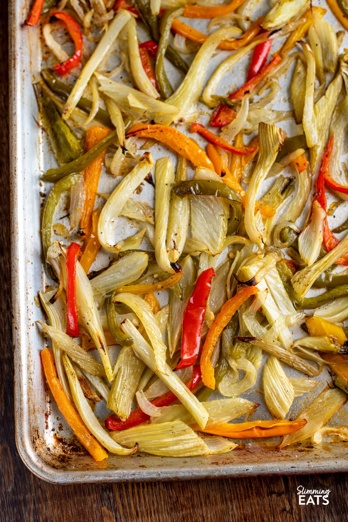 Roasted fennel and peppers is a delicious and nutritious side dish, combining the earthy aniseed flavor of fennel with the sweet essence of bell peppers, all complemented by the aromatic presence of onion and garlic. Roasted Fennel and Mixed Peppers on a baking tray lined with parchment