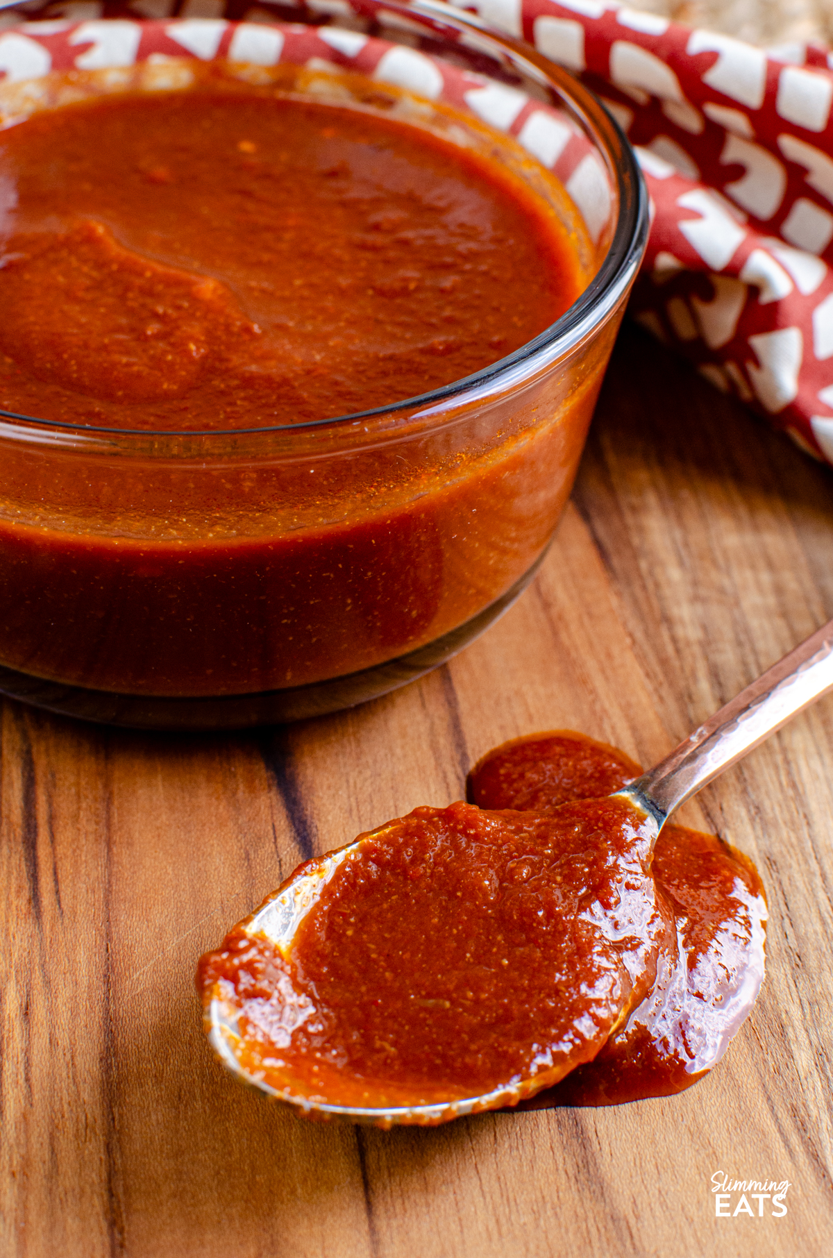 Homemade Barbecue Sauce in a glass bowl with sauce on a spoon 
