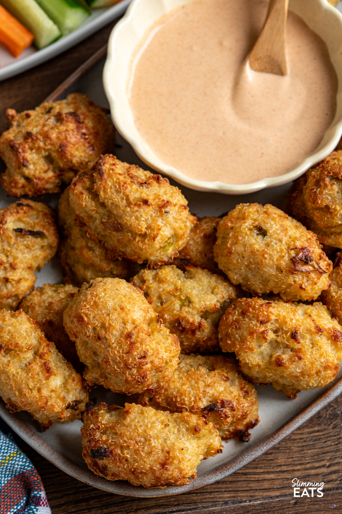 close up of Cheddar Apple Quinoa Bites on a oval brown grey plate with a honey sriracha dip