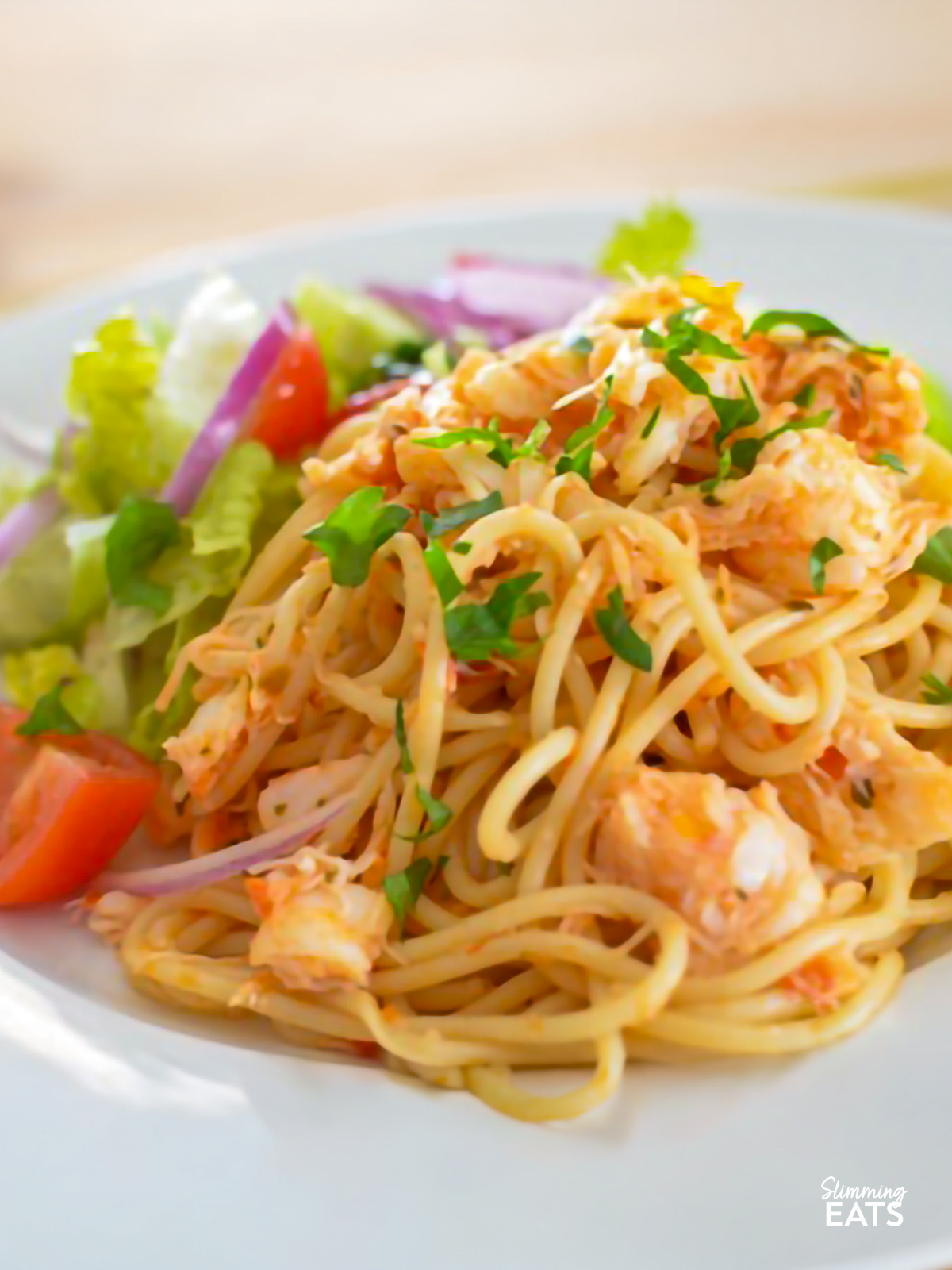 crab red pesto spaghetti with salad on a white plate