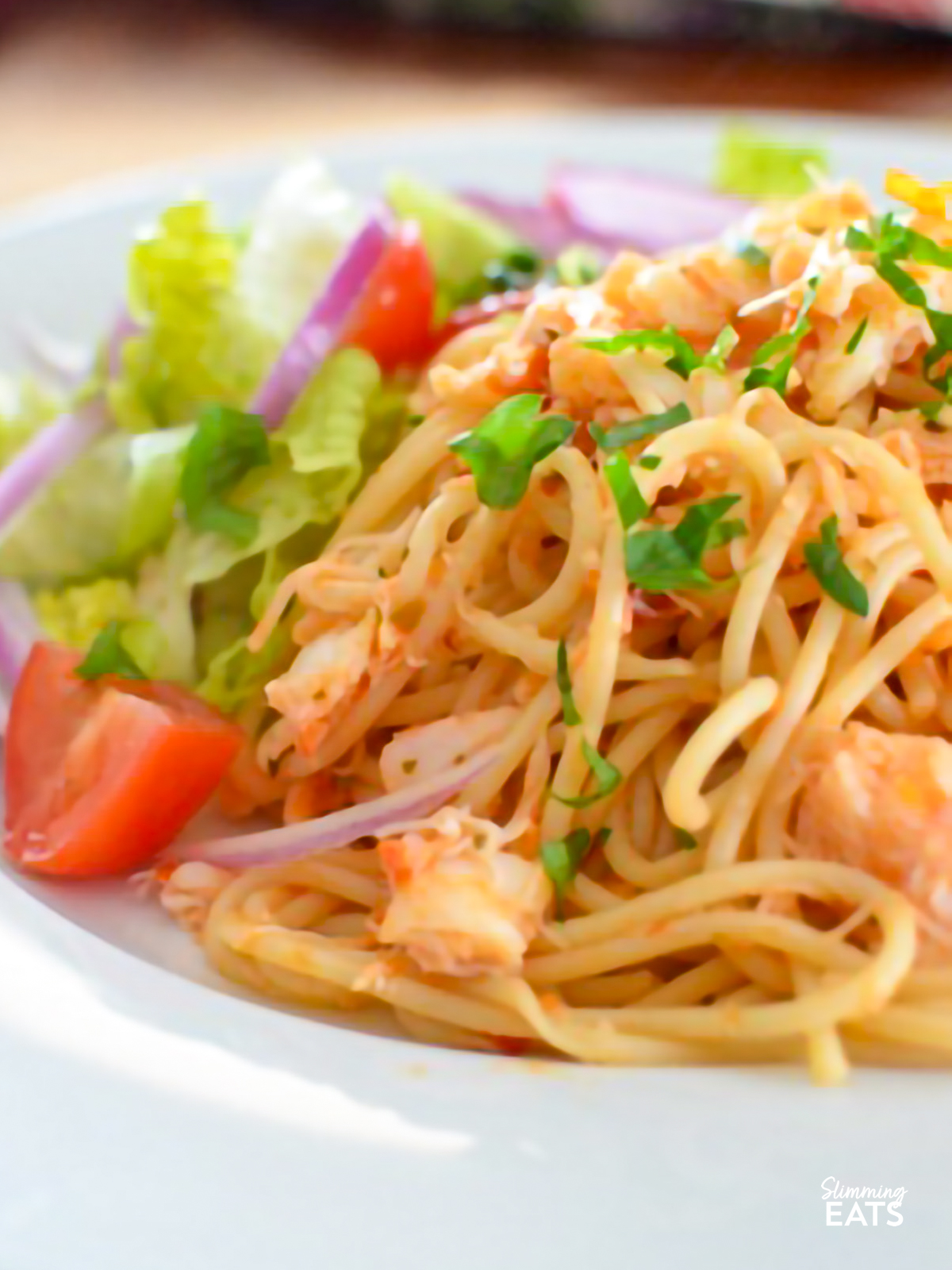 crab red pesto spaghetti with salad on a white plate