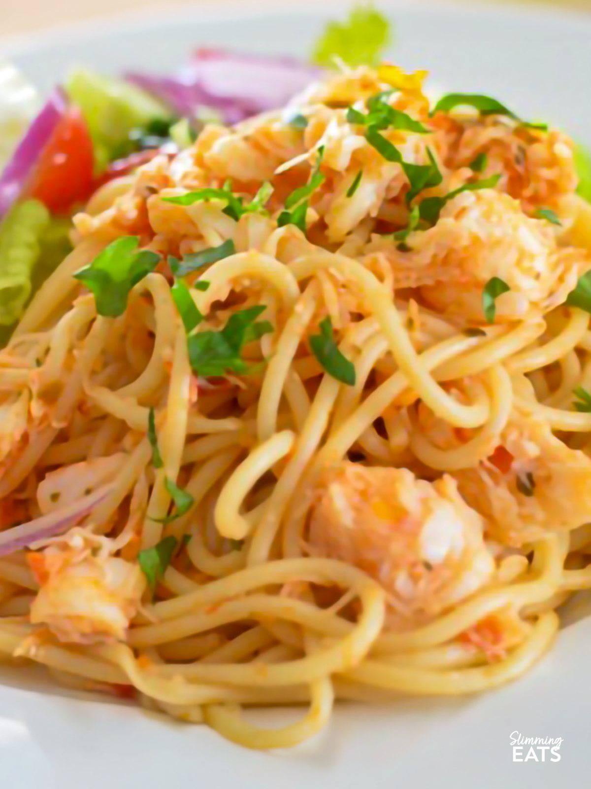 crab red pesto spaghetti with salad on a white plate