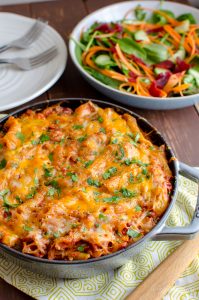 tuna pasta bake in cast iron skillet with salad and white plate in background
