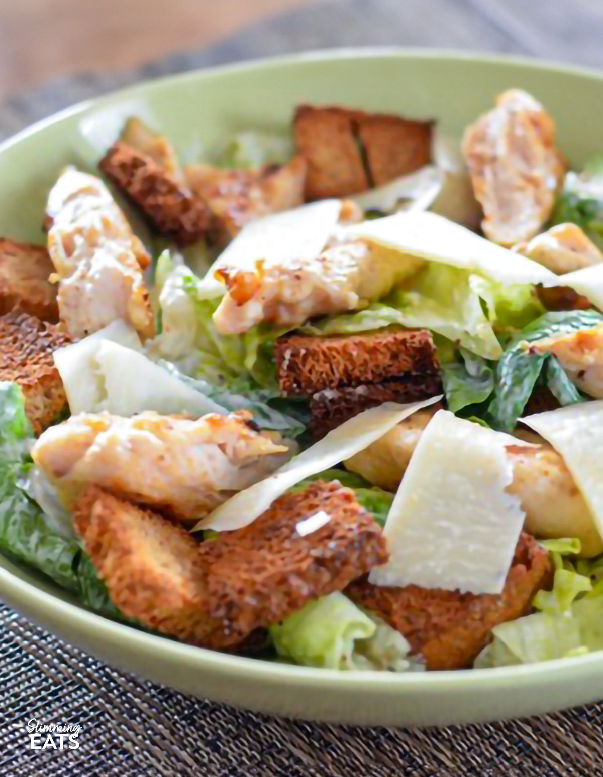 Enjoy a fresh and flavour-packed Chicken Caesar Salad that keeps things light without compromising on taste. This homemade version swaps heavy ingredients for a balanced mix of crisp romaine, tender seasoned chicken, and a creamy, lower-calorie Caesar dressing that still delivers that classic, garlicky flavour. close up of Easy Chicken Caesar Salad in a light green bowl