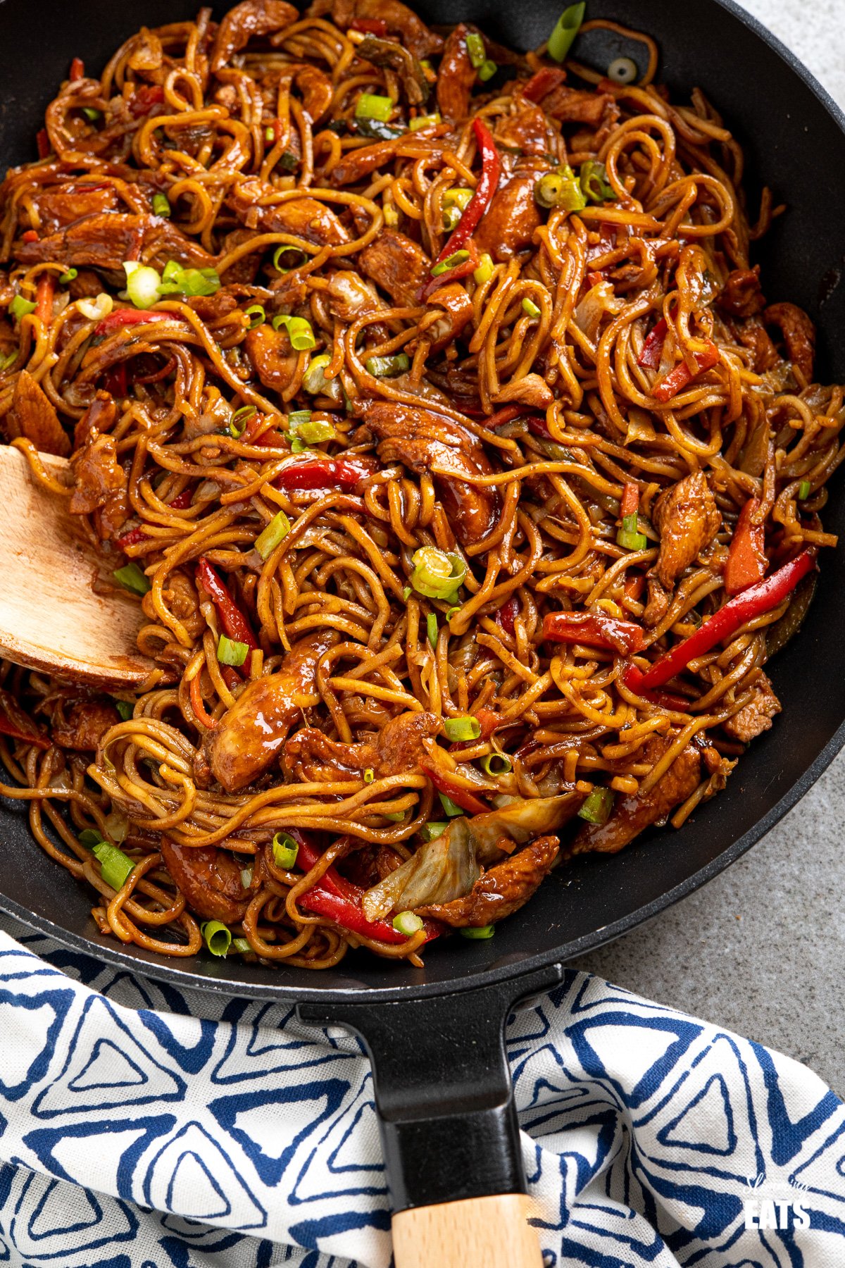 close up of Hoisin Chicken with noodle in black frying pan with wooden handle