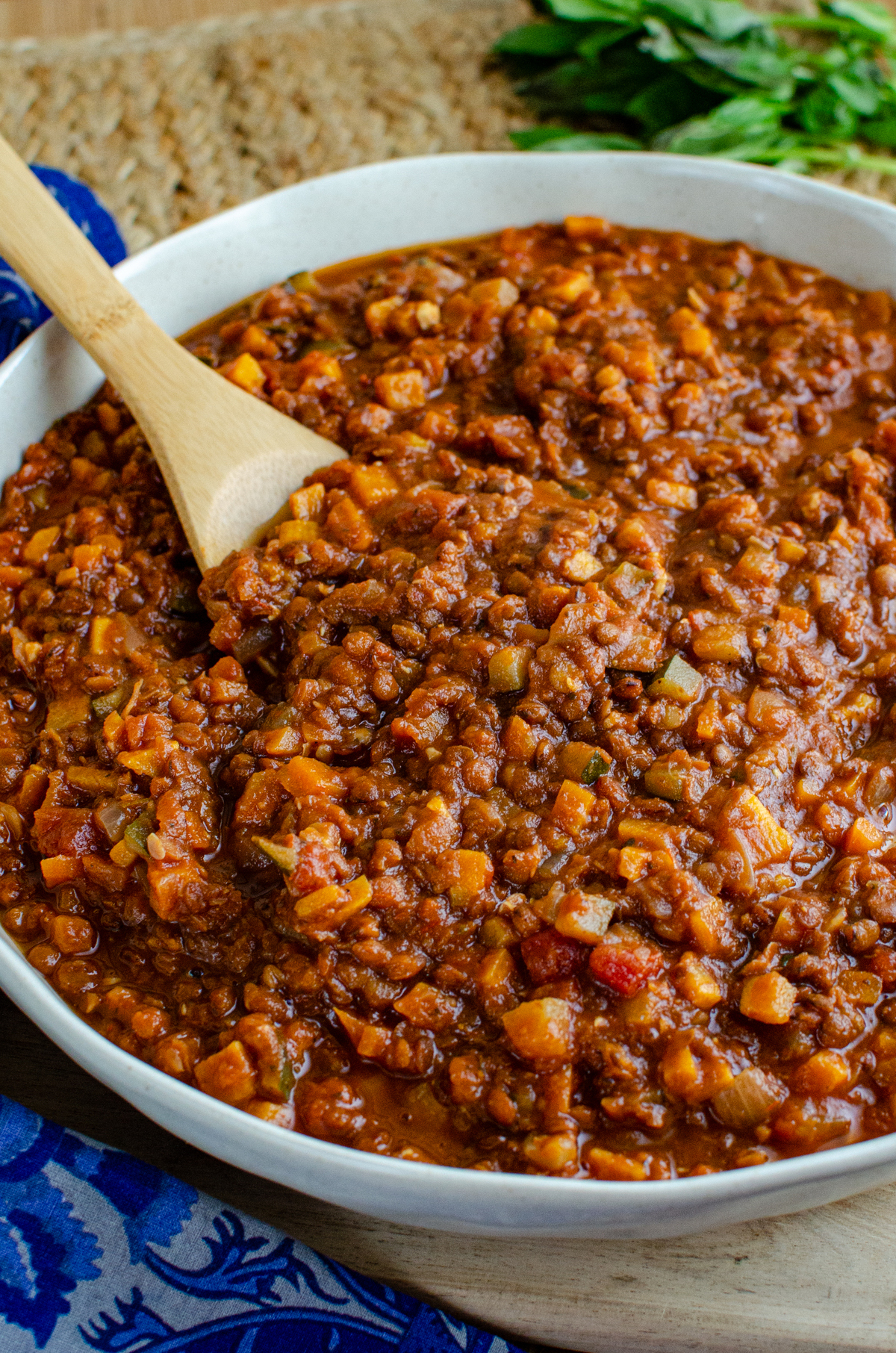 Lentil Bolognese - a hearty comforting meat free bolognese packed with lentils, vegetables and rich tomato flavour that is perfect for family dinners and batch cooking. It is filling, budget friendly and a great way to turn a simple bag of lentils into something really delicious. Lentil Bolognese in a round dish with wooden spoon