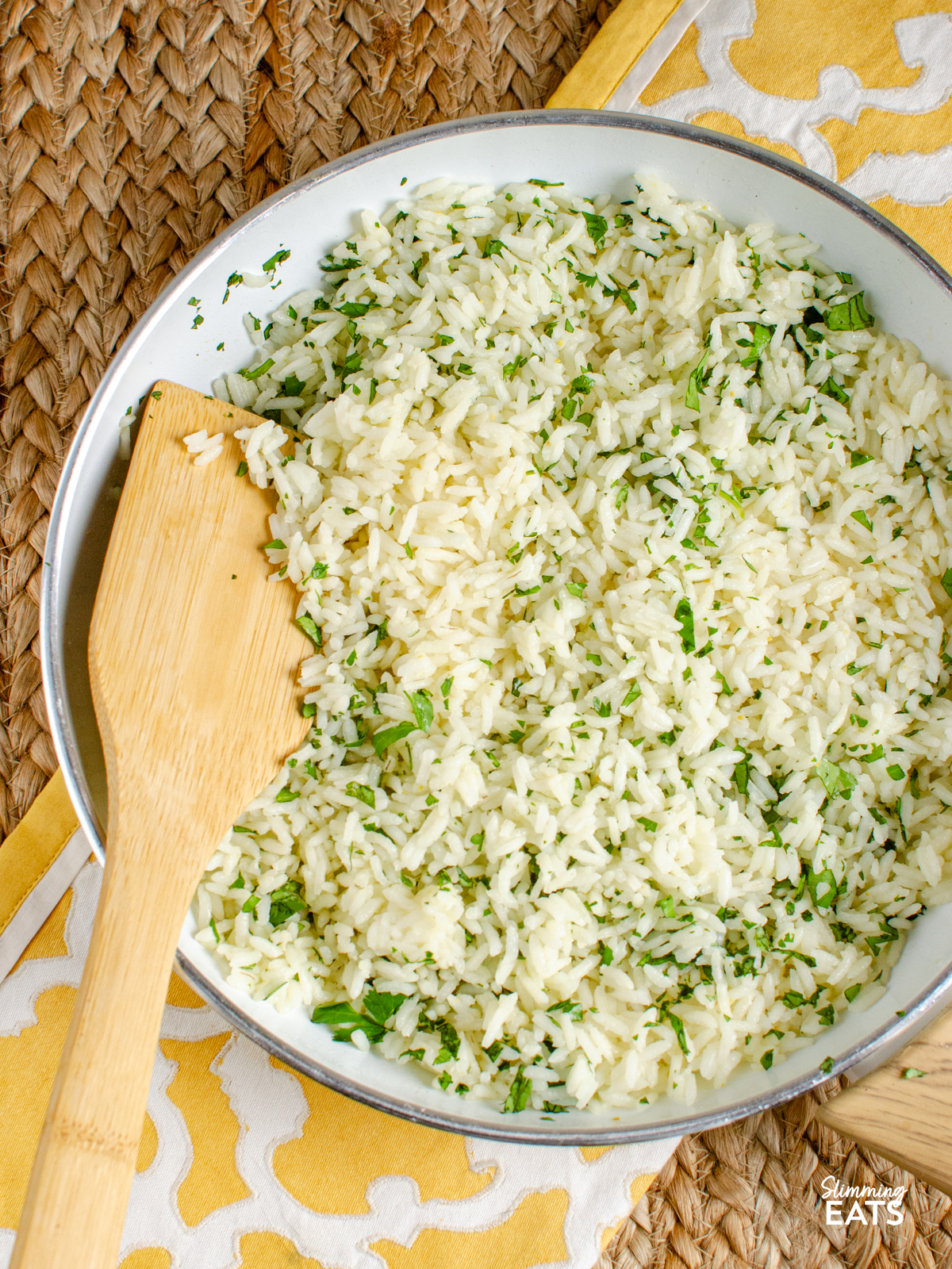 lime cilantro rice in a white non stick frying pan with wooden spoon