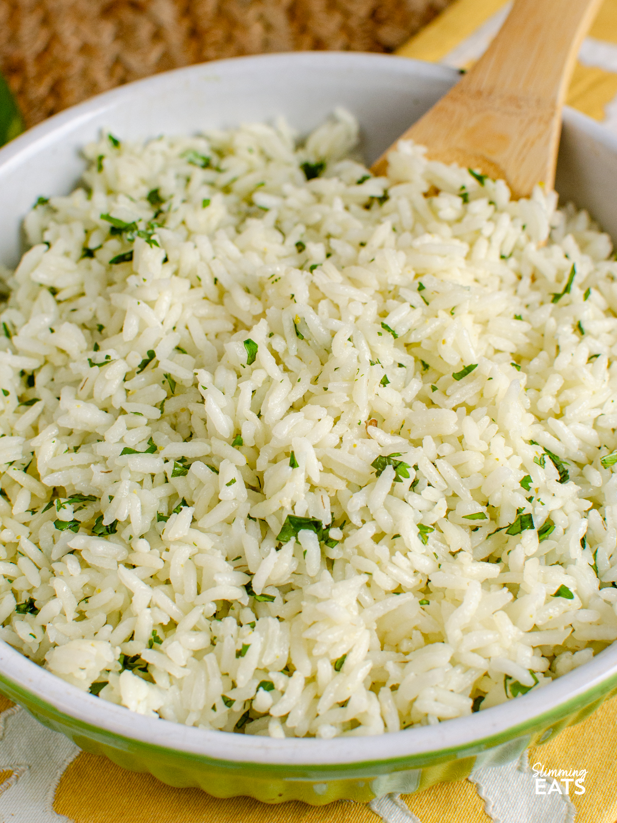 lime cilantro rice in a white and lime green bowl with wooden spoon