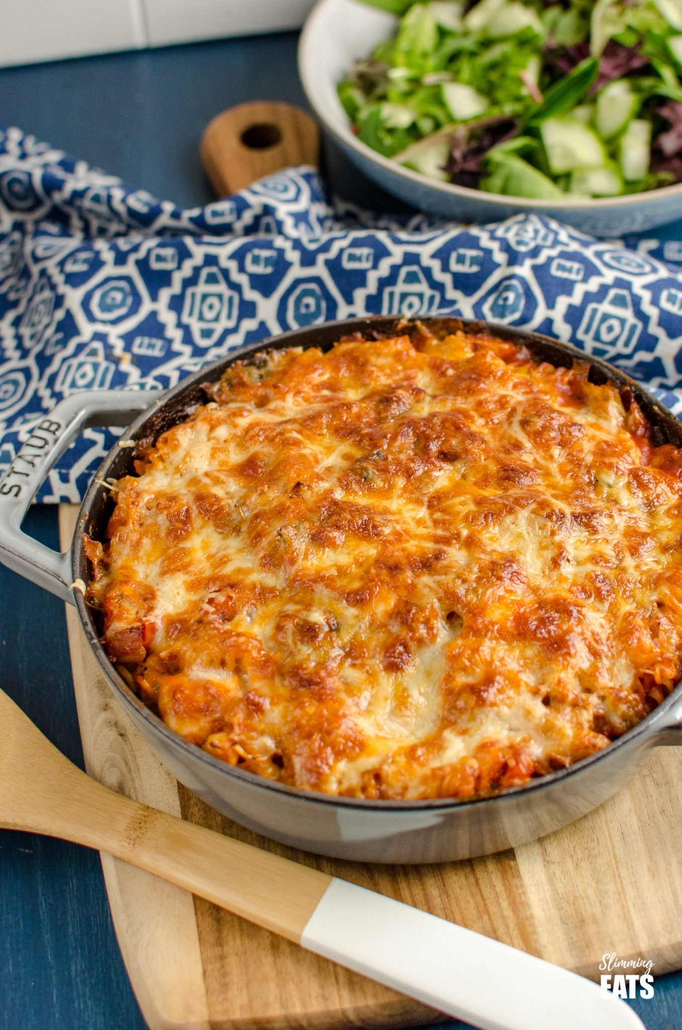 Salmon and Leek Pasta Bake is grey cast iron staub skillet with bowl of salad in background