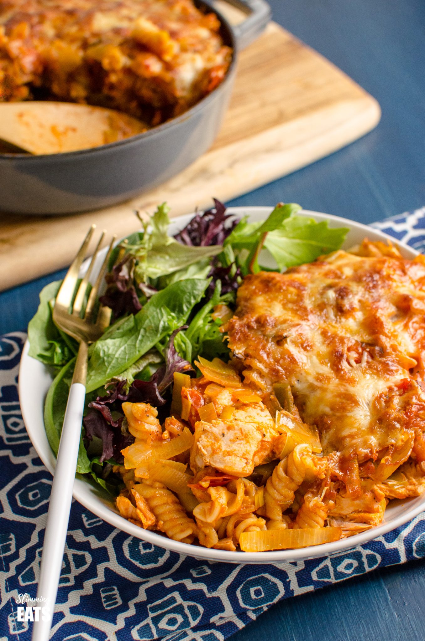 Salmon and Leek Pasta Bake in white bowl with baby greens. 