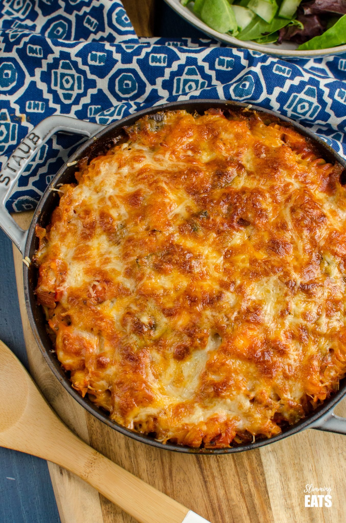 Salmon and Leek Pasta Bake is grey cast iron staub skillet with bowl of salad in background