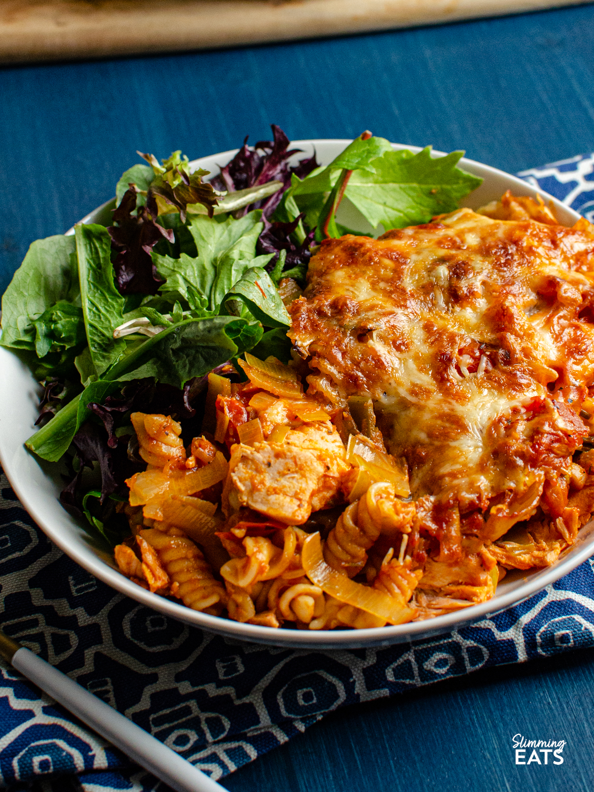 Salmon and Leek Pasta Bake - Salmon and Leek Pasta Bake - a delicious recipe using fresh salmon, sauteed leeks and a homemade tomato pasta sauce, all finished off with melted cheesy goodness - yum!! Slimming Eats and Weight Watchers friendly Salmon and Leek Pasta Bake in white bowl with baby greens.