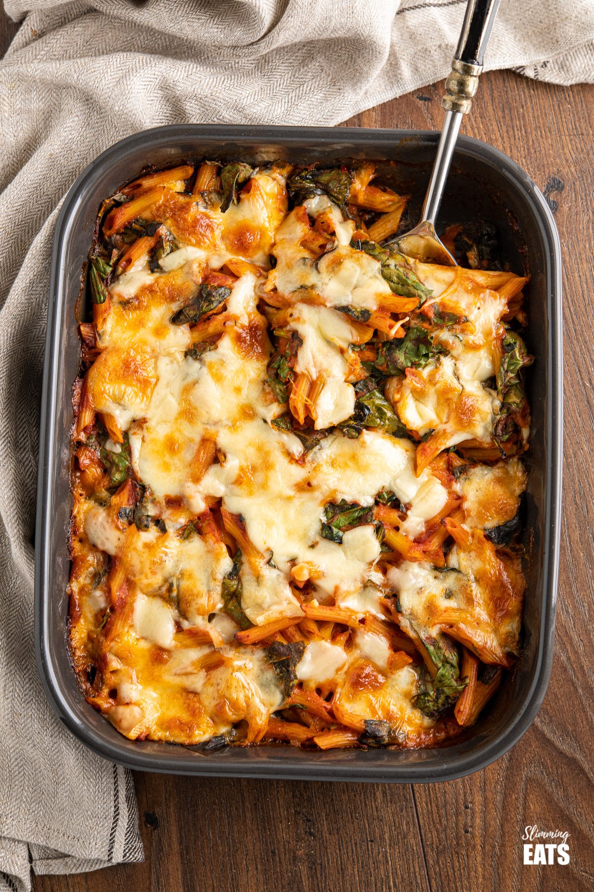 spinach pasta baked in grey oven dish on wooden board