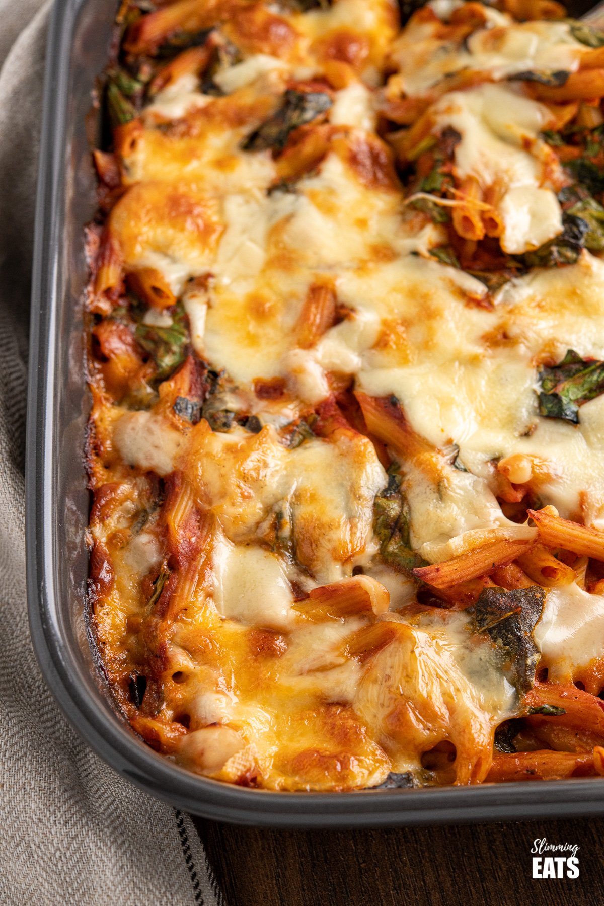 close up of spinach pasta bake in dark grey oven dish