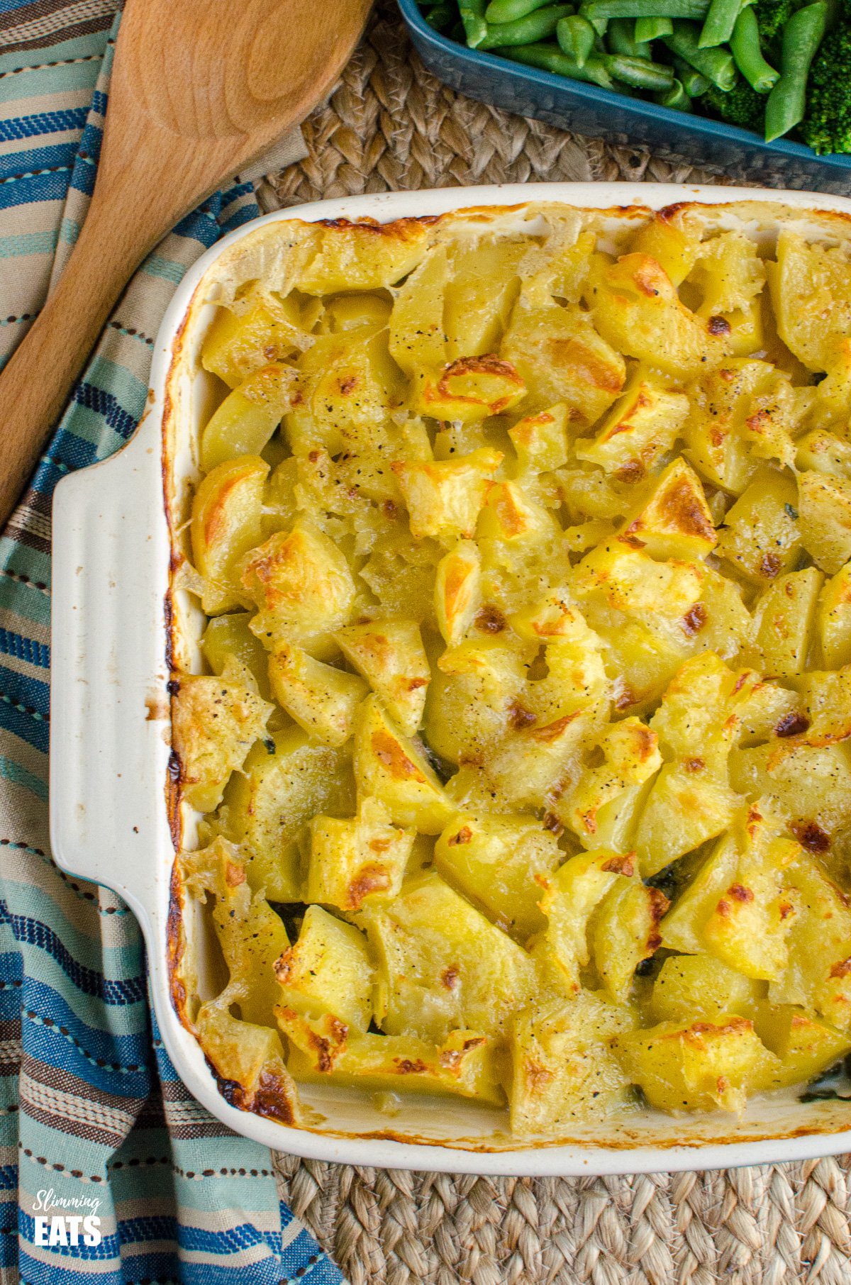 Creamy Chicken and Spinach Pie with a delicious golden rustic potato topping and creamy sauce this pie makes a perfect family meal. Gluten free, Slimming Eats and Weight Watchers friendly over the top view Creamy Chicken and Spinach Pie in oven dish with wooden spoon placed to the side