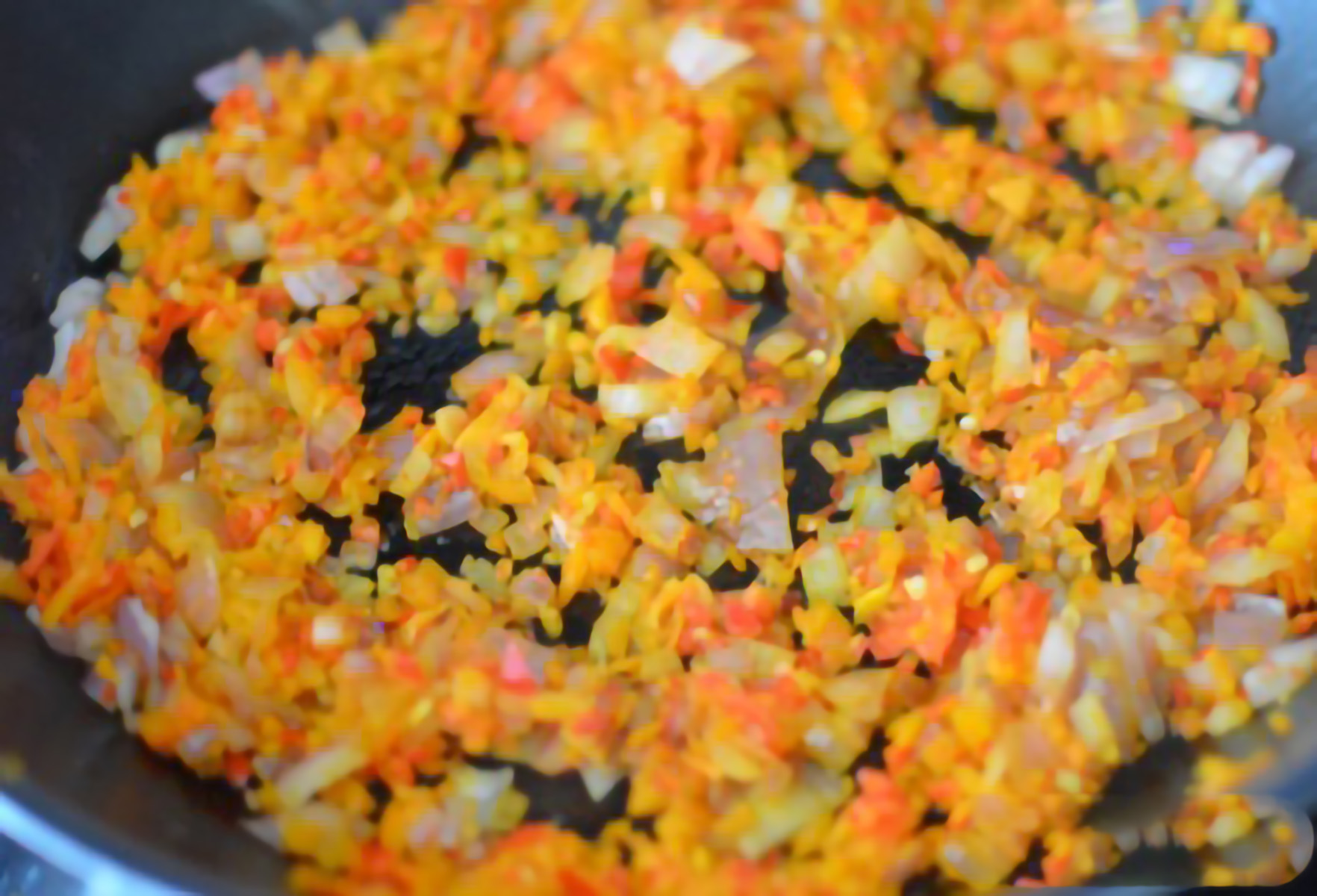 ONIONS, PEPPERS AND GARLIC BEING SAUTEED IN A PAN