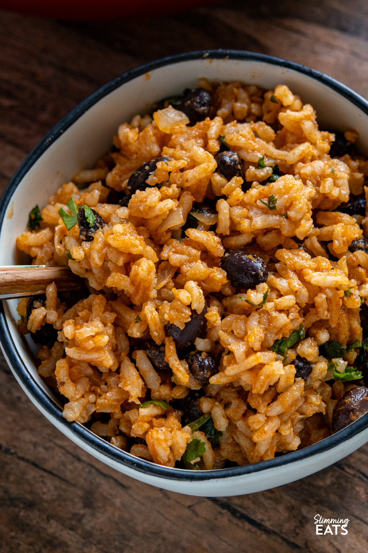 Mexican Rice - a flavour packed rice dish with spicy tomato flavours, black beans and a little kick of jalapeño that makes the perfect side for all your favourite Mexican inspired meals. It is easy to make, full of colour and delicious enough to enjoy all on its own. close up Mexican Rice in a small white bowl with black rim
