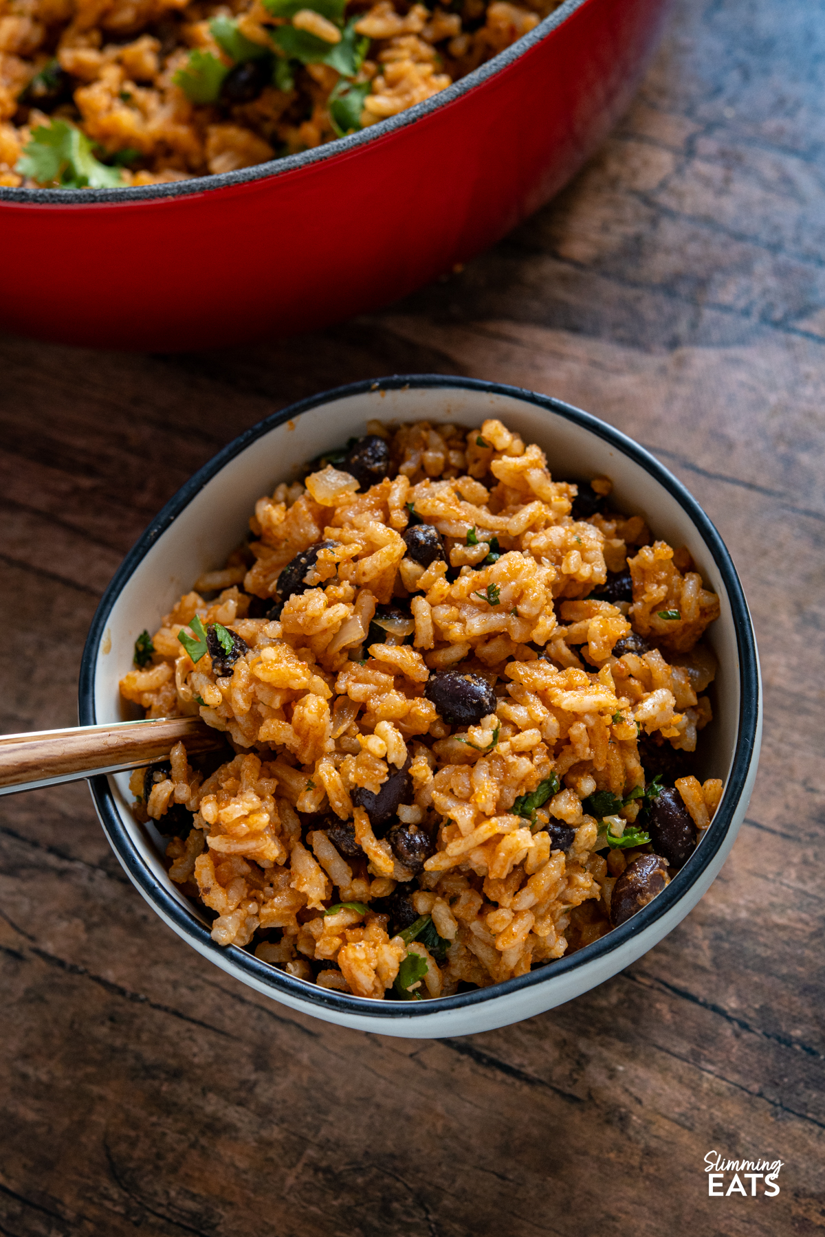 Mexican Rice - a flavour packed rice dish with spicy tomato flavours, black beans and a little kick of jalapeño that makes the perfect side for all your favourite Mexican inspired meals. It is easy to make, full of colour and delicious enough to enjoy all on its own. Mexican Rice in a small white bowl with black rim