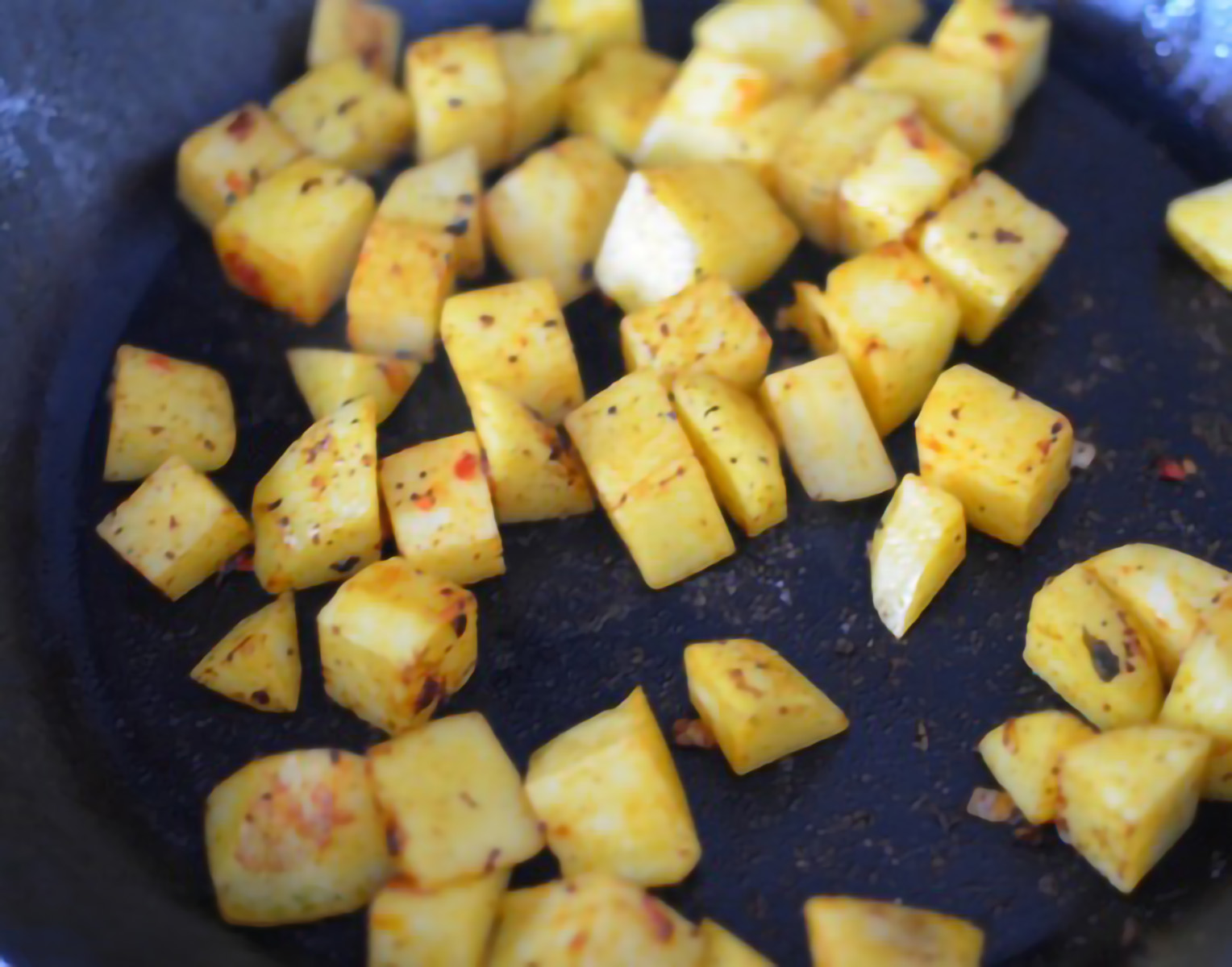 seasoned potatoes being fried in a pan