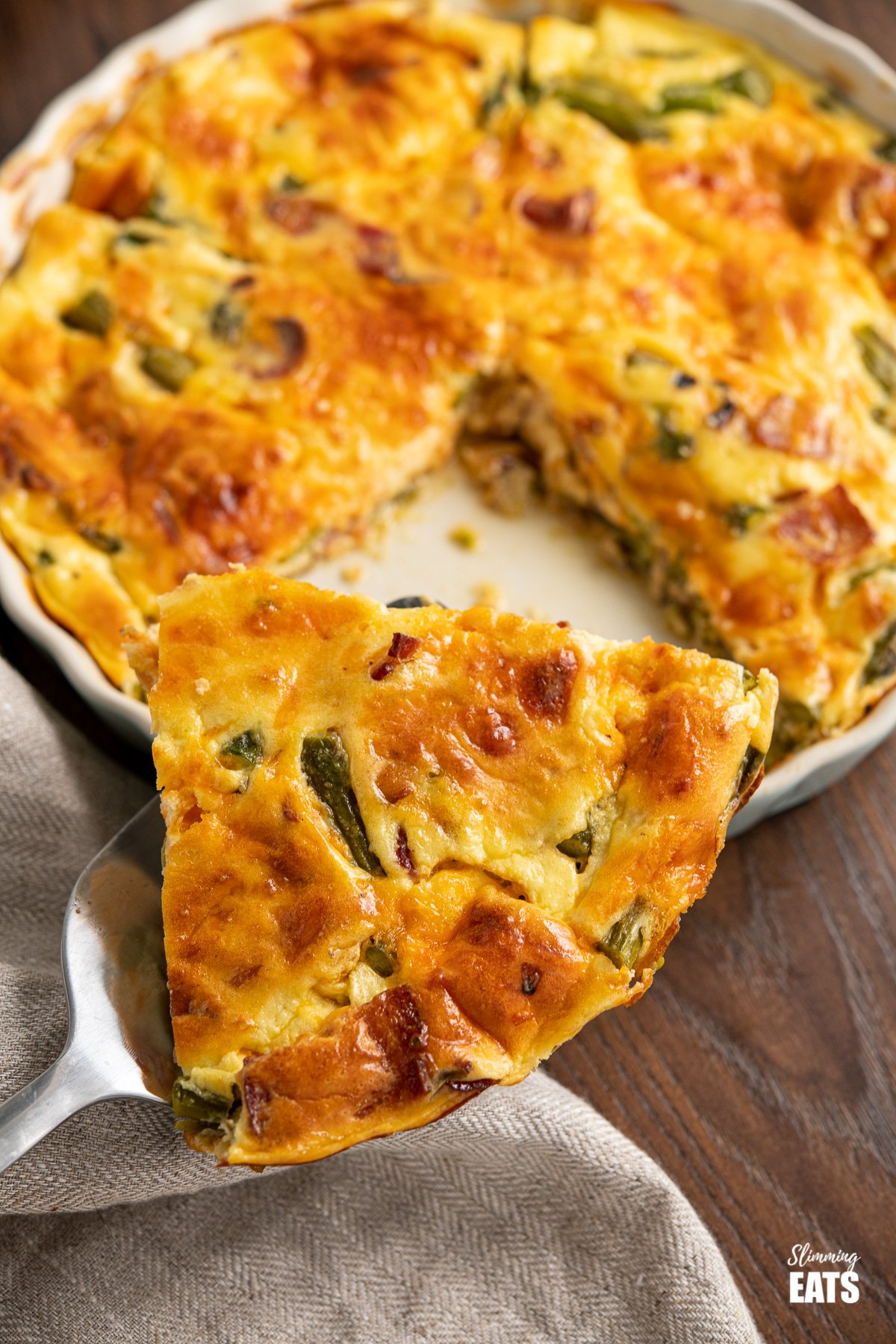 slice of Crustless Asparagus and Bacon Quiche on spatula from flan dish