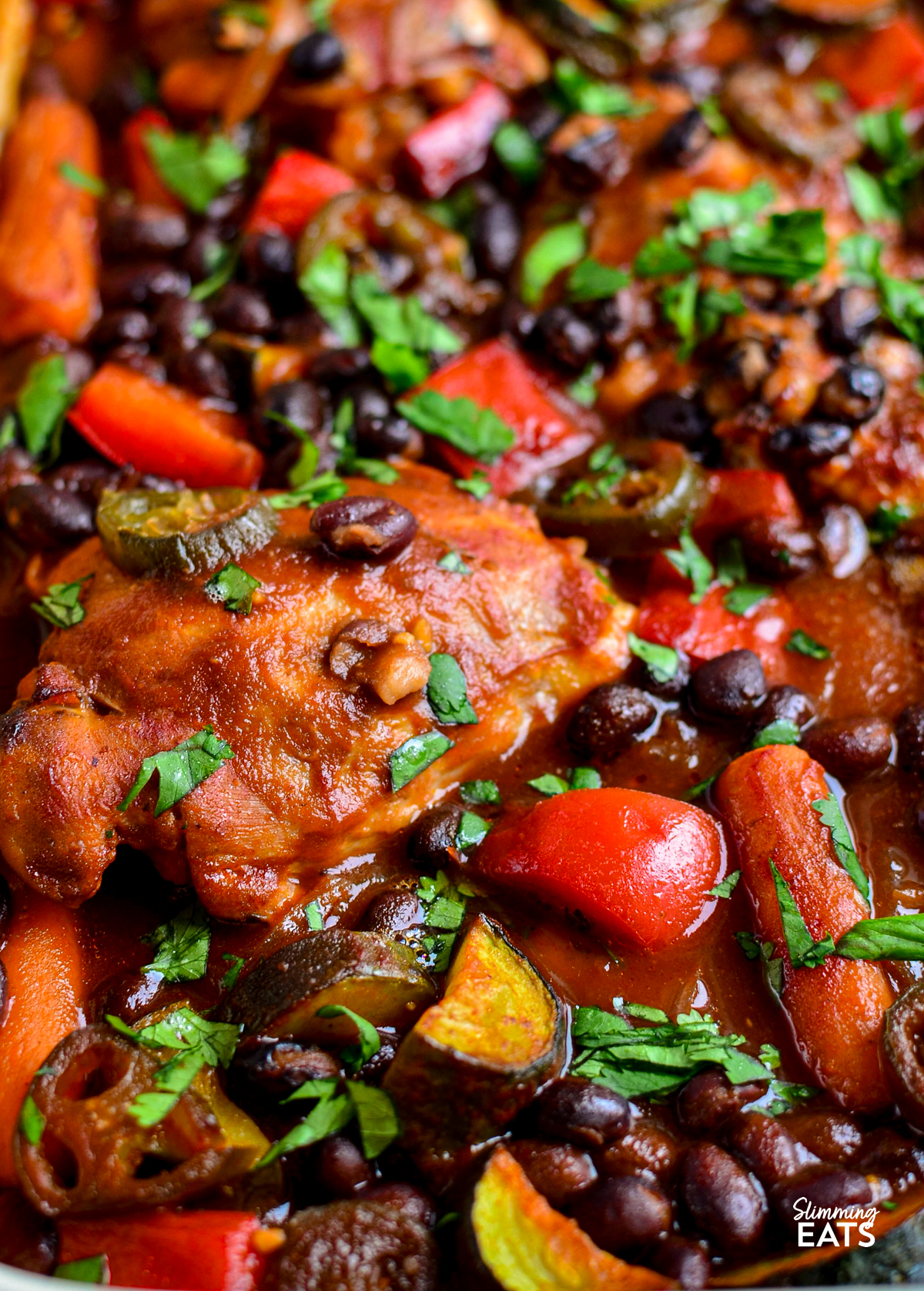 close up of kickin barbecue chicken in a ceramic  baking dish garnished with cilantro