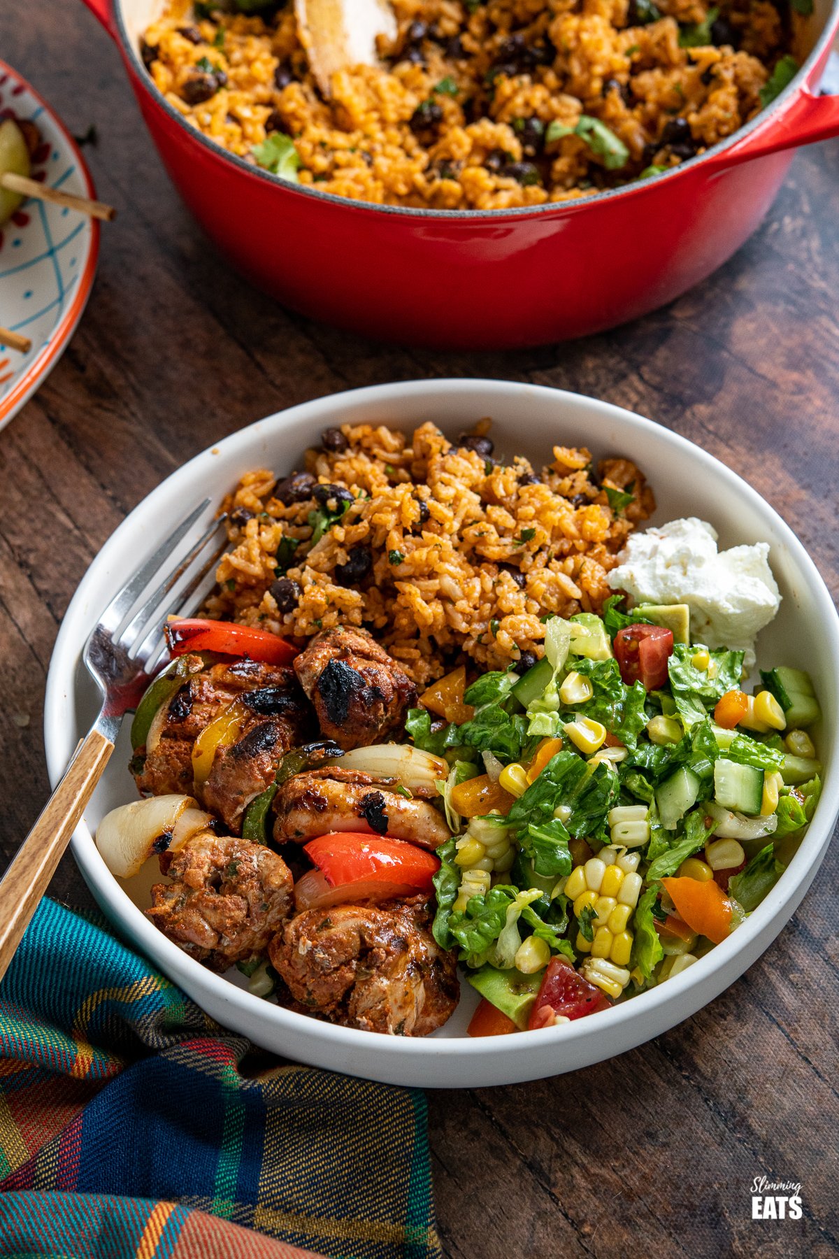 Mexican Barbecue - tender chicken skewers marinated with a delicious Mexican blend of spices for the perfect barbecue meal. mexican chicken in a grey brown bowl with rice, sour cream and salad