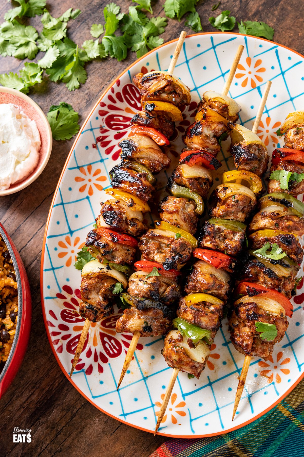 close up of chicken skewers on a oval patterned plate 