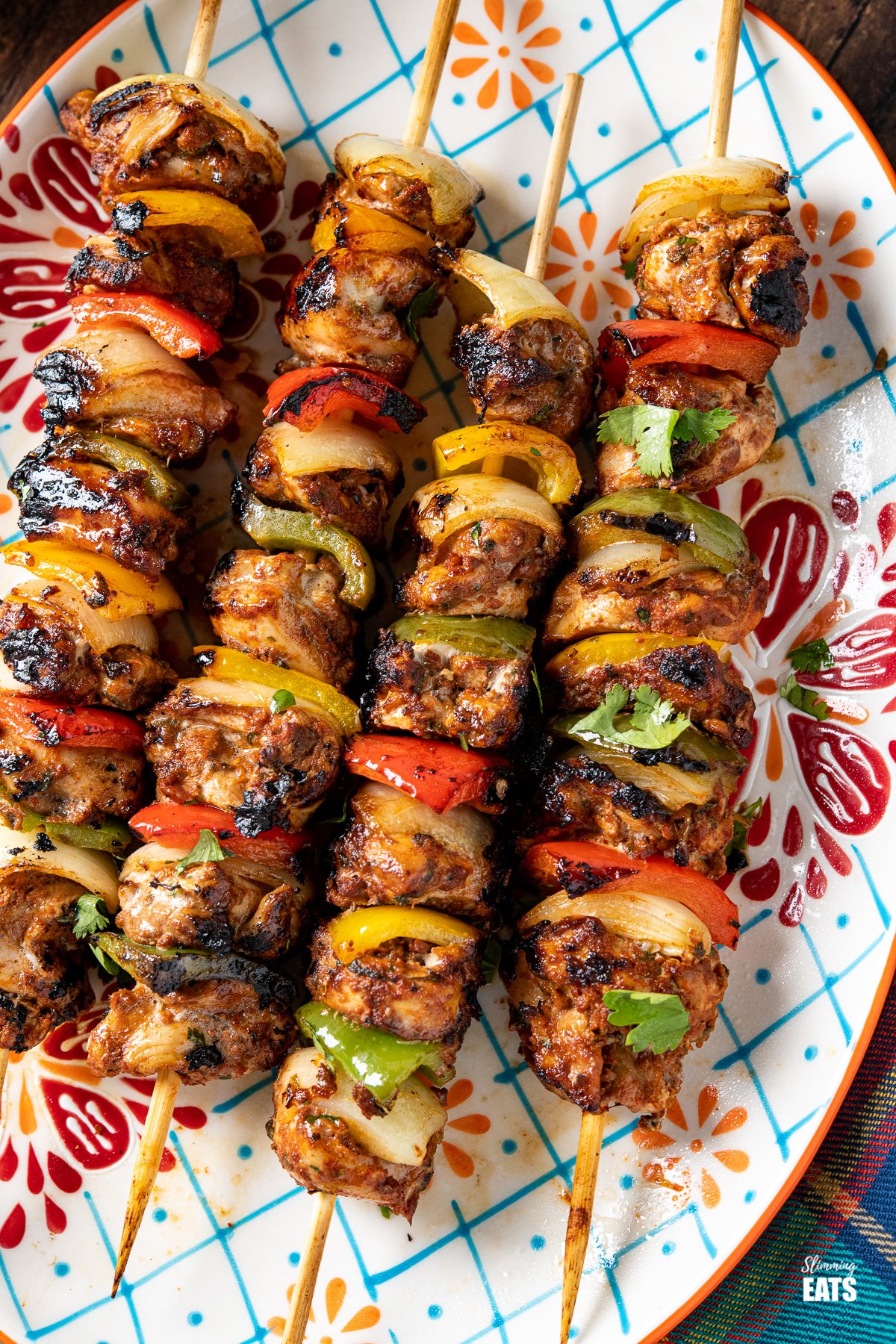 close up of chicken skewers on a oval patterned plate