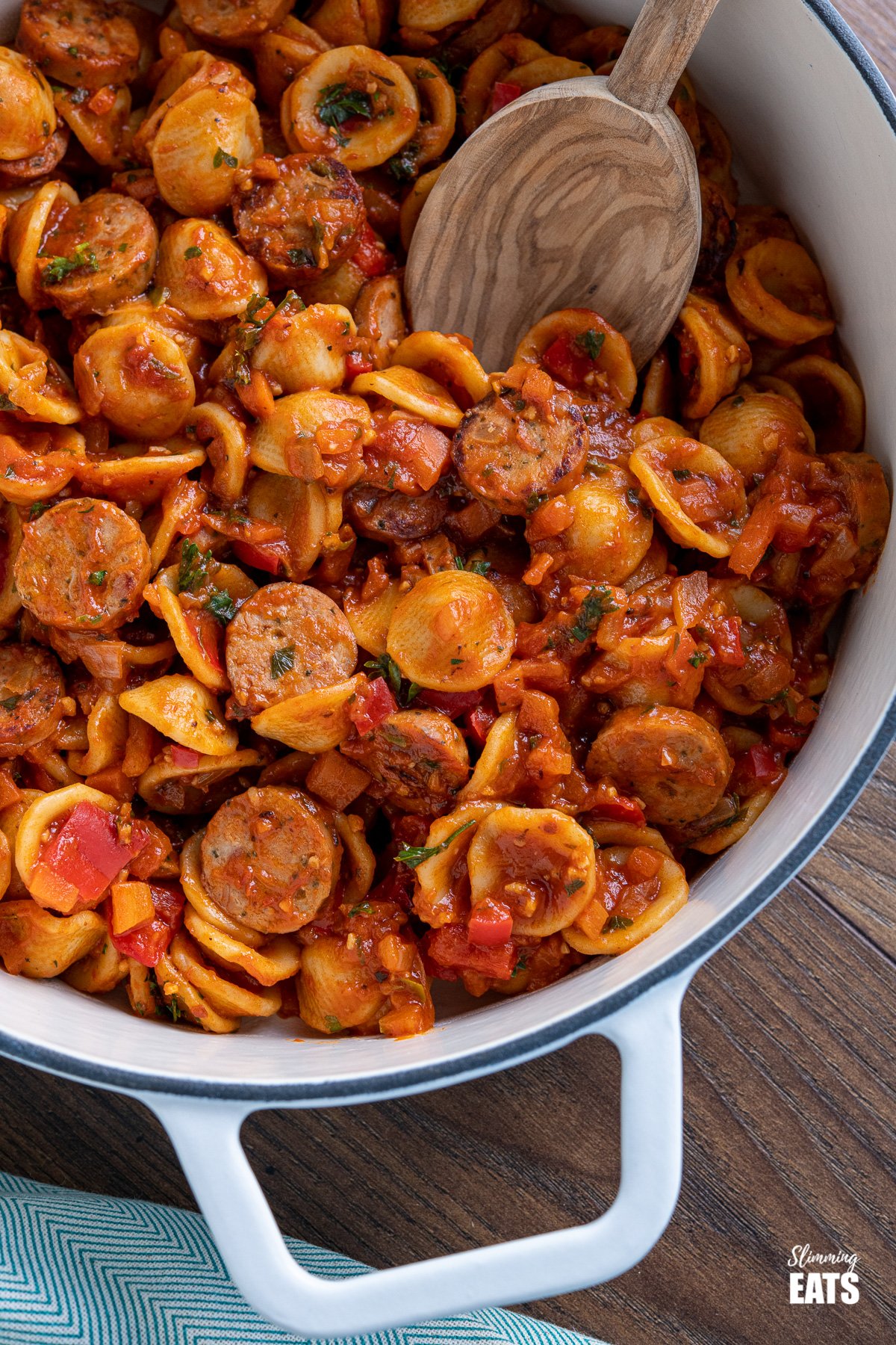 Orecchiette with Smoked Turkey Sausage - delicious bites of smoked sausage in rich tomato sauce with vegetables and orecchiette pasta. Slimming Eats and Weight Watchers friendly close up of Orecchiette with Smoked Turkey Sausage in a white cast iron skillet with olive wood spoon