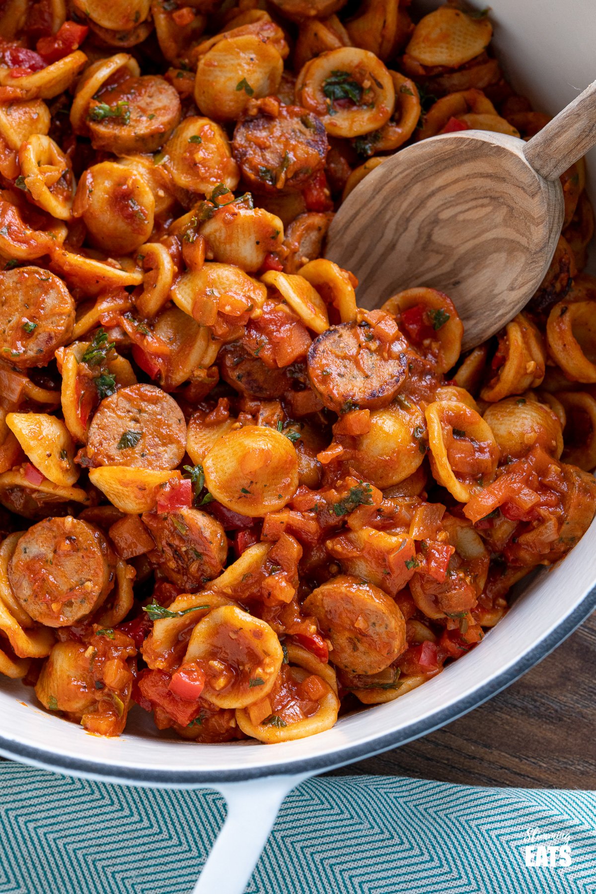 Orecchiette with Smoked Turkey Sausage - delicious bites of smoked sausage in rich tomato sauce with vegetables and orecchiette pasta. Slimming Eats and Weight Watchers friendly close up of Orecchiette with Smoked Turkey Sausage in a white cast iron skillet with olive wood spoon