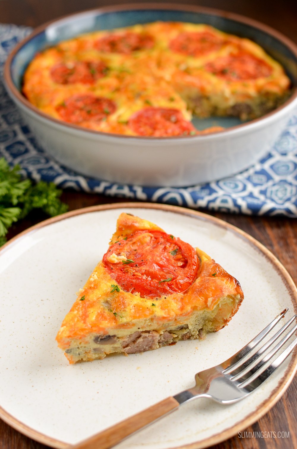 slice of breakfast quiche on a white plate with fork