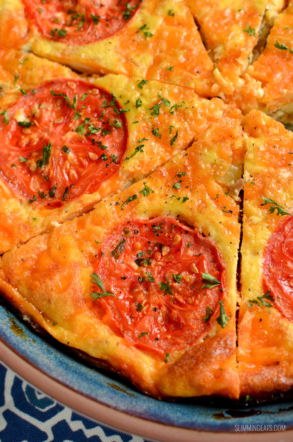 close up of sliced breakfast quiche topped with tomato slices