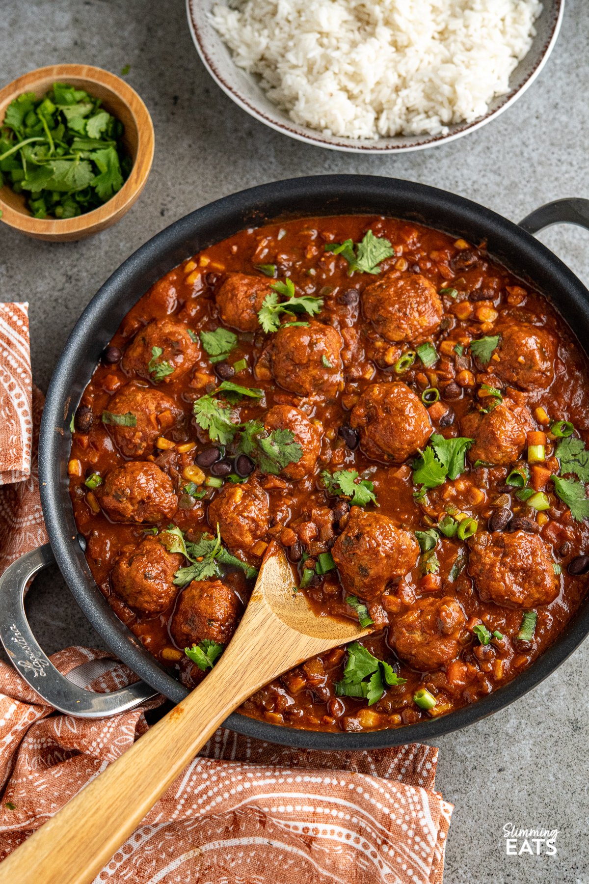 Southwestern Turkey Meatballs - delicious turkey meatballs in a amazing spicy Southwestern Style Sauce with black beans, corn and veggies. Low Calorie and Slimming Friendly southwestern turkey meatballs in frying pan with double handles, bowl of rice in background