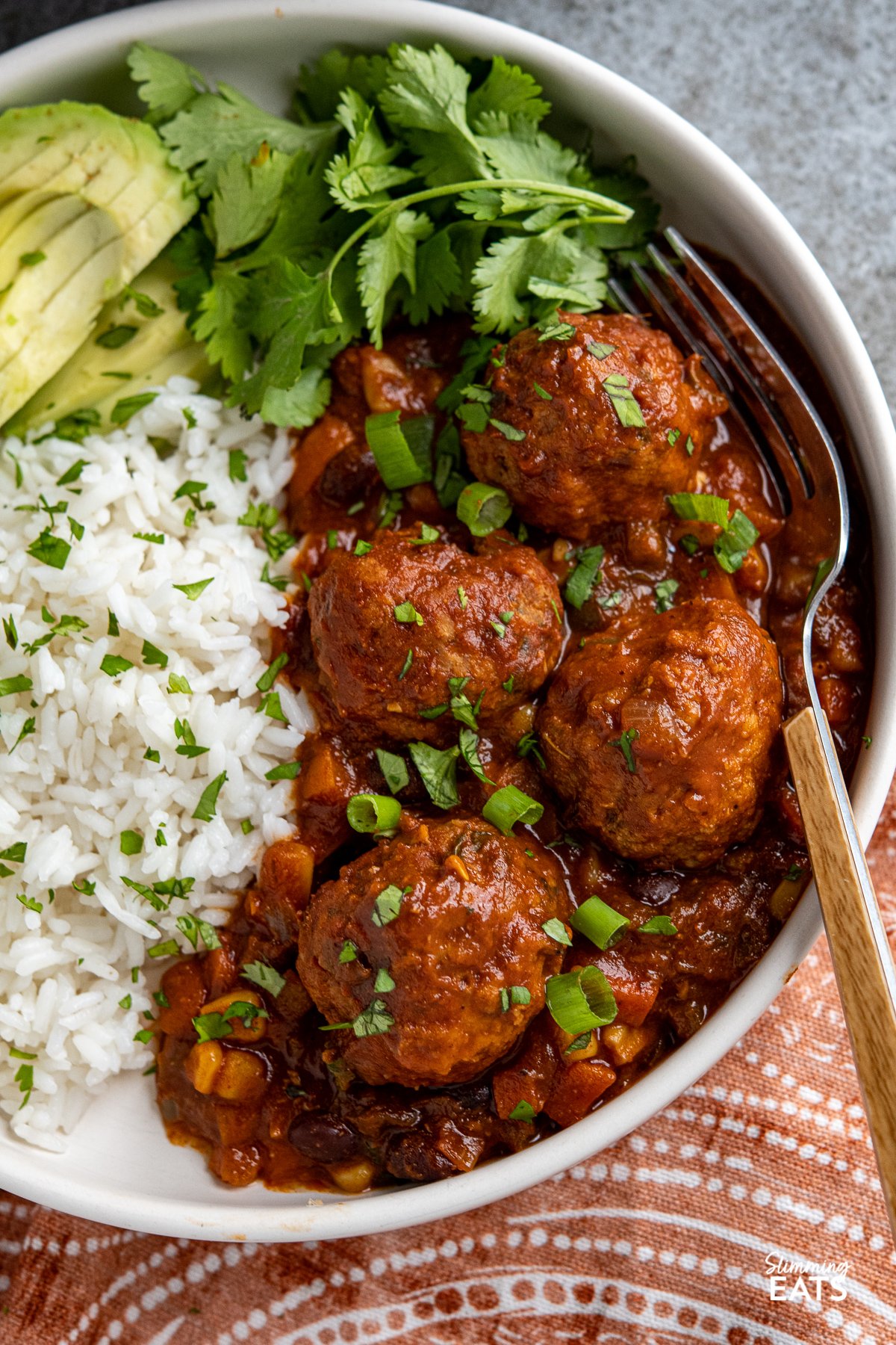 Southwestern Turkey Meatballs - delicious turkey meatballs in a amazing spicy Southwestern Style Sauce with black beans, corn and veggies. Low Calorie and Slimming Friendly close up of Southwestern turkey meatballs in a bowl with rice, avocado and cilantro