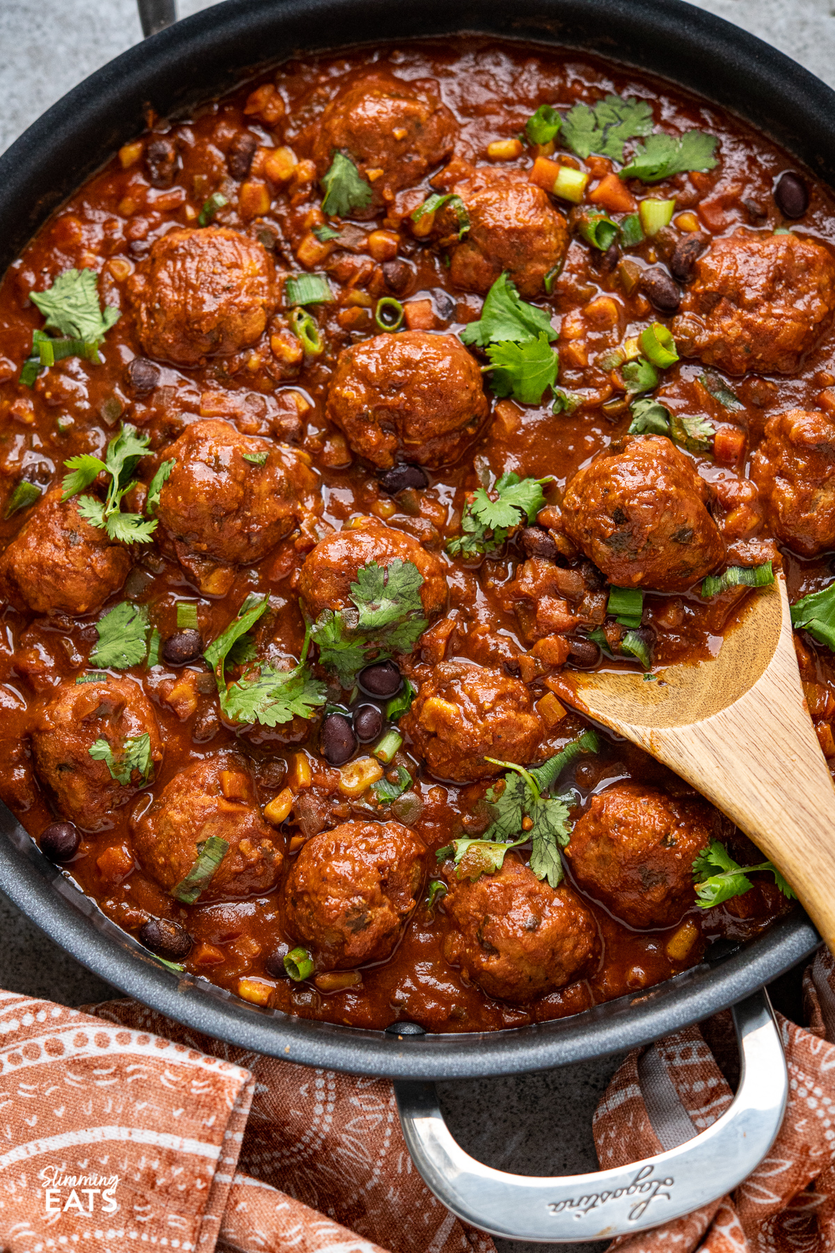 close up of wooden spoon scooping southwestern turkey meatballs from frying pan