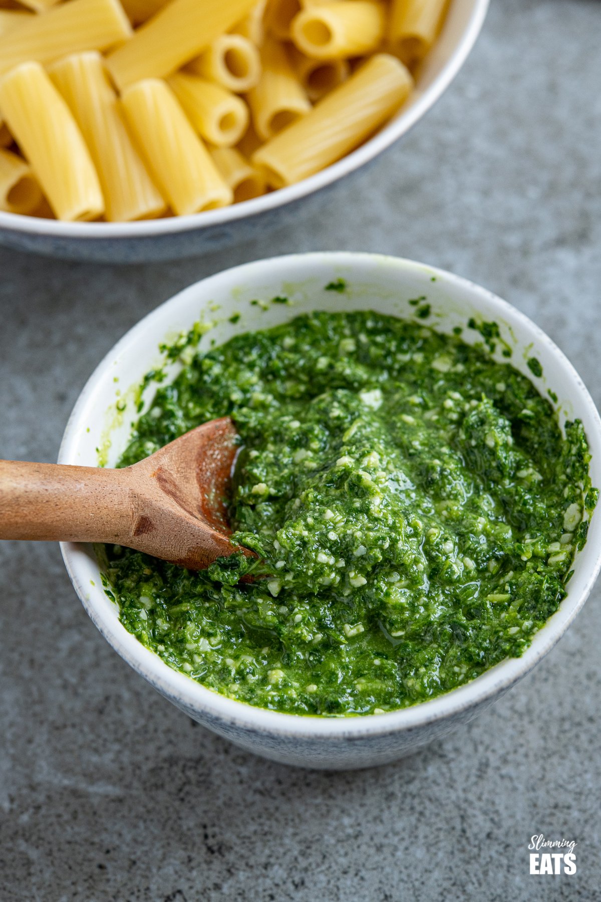 close up of skinny pesto in a white bowl with blue speckled pattern