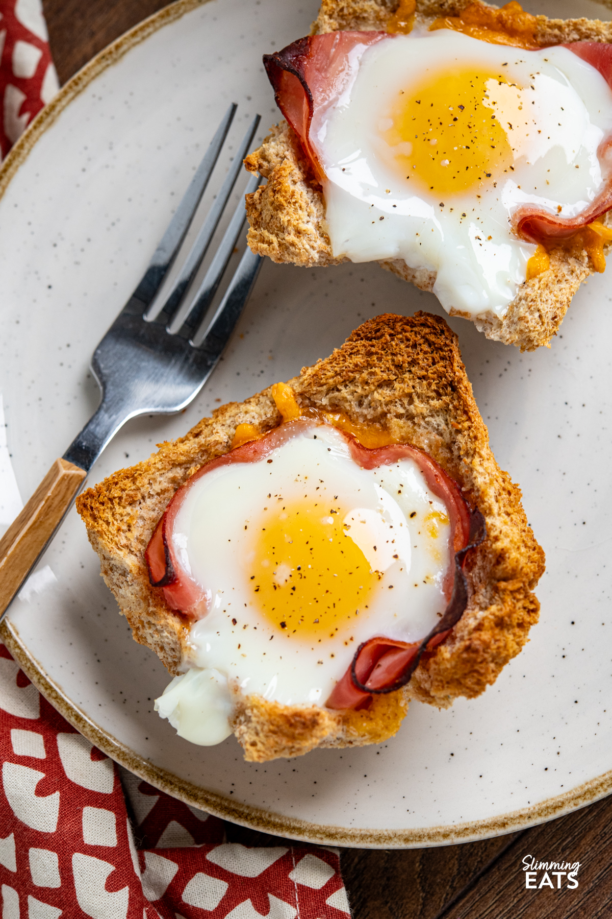 close up of two Egg, Ham and Cheese Toast Baskets on a plate with a fork