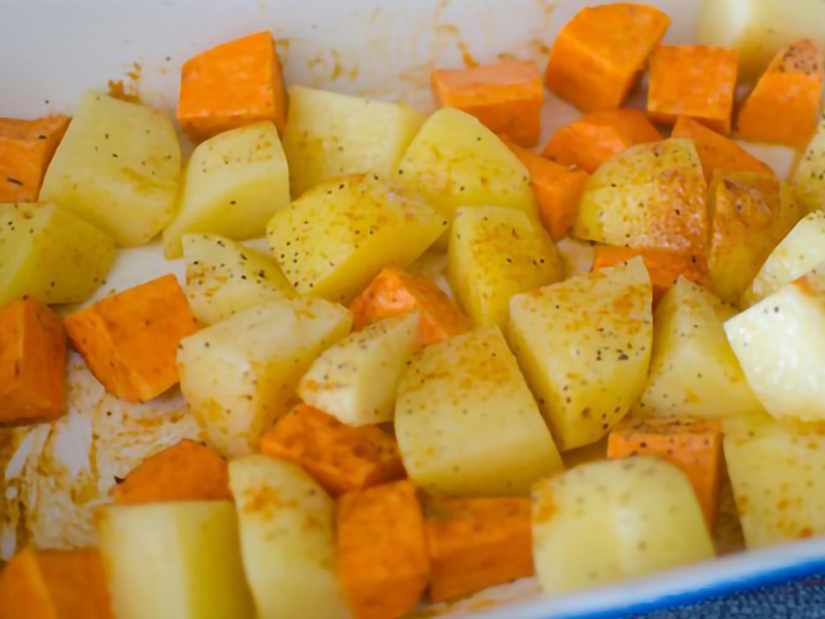 potatoes and sweet potatoes seasoned and ready to be roasted in a baking dish